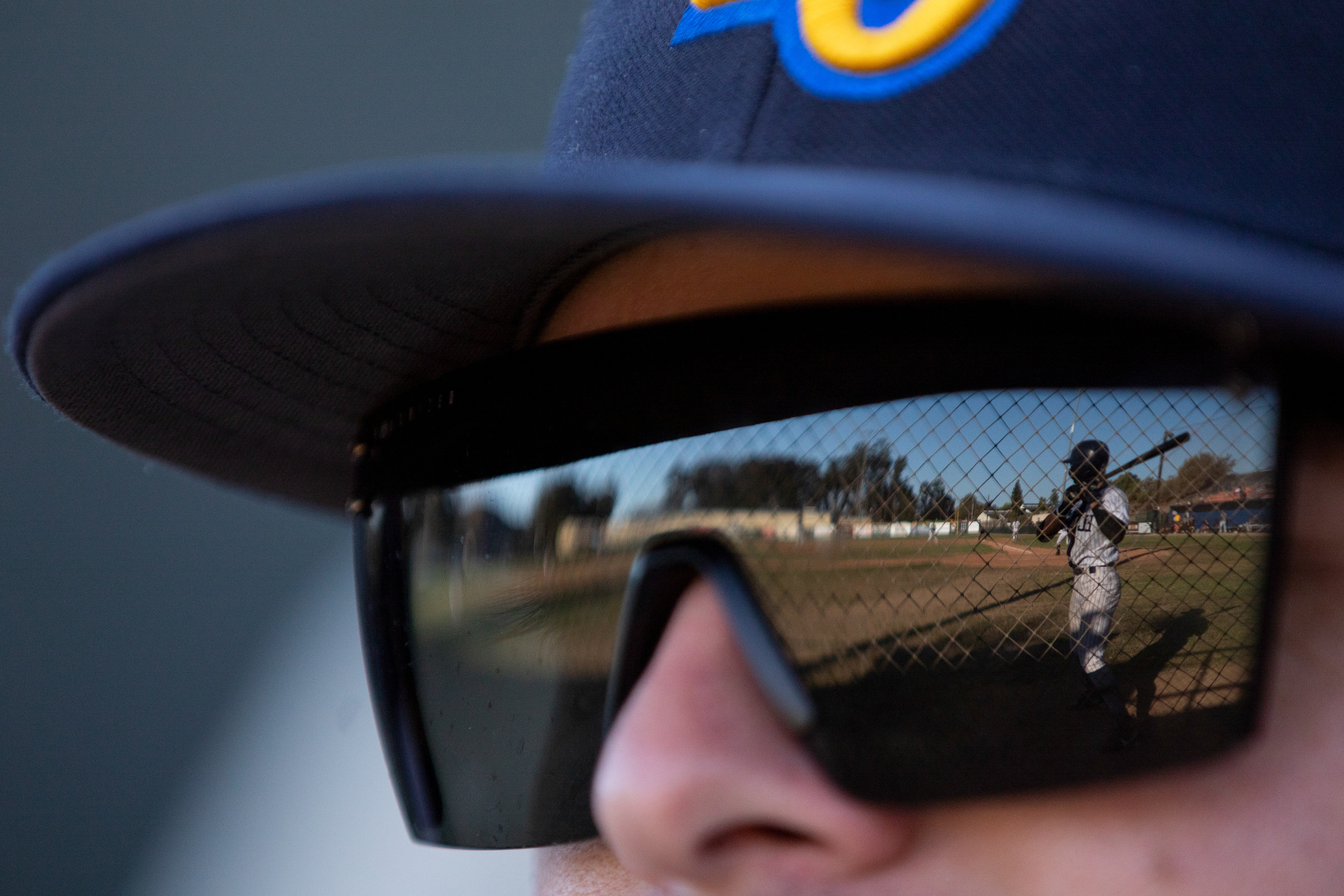 SLO Blues Athletic trainer Jared Rosales looks at the field where 2B Diego Murillo (7) stands on deck during the game against the Arroyo Seco Saints at Sinsheimer Stadium in San Luis Obispo, California on July 1, 2025.