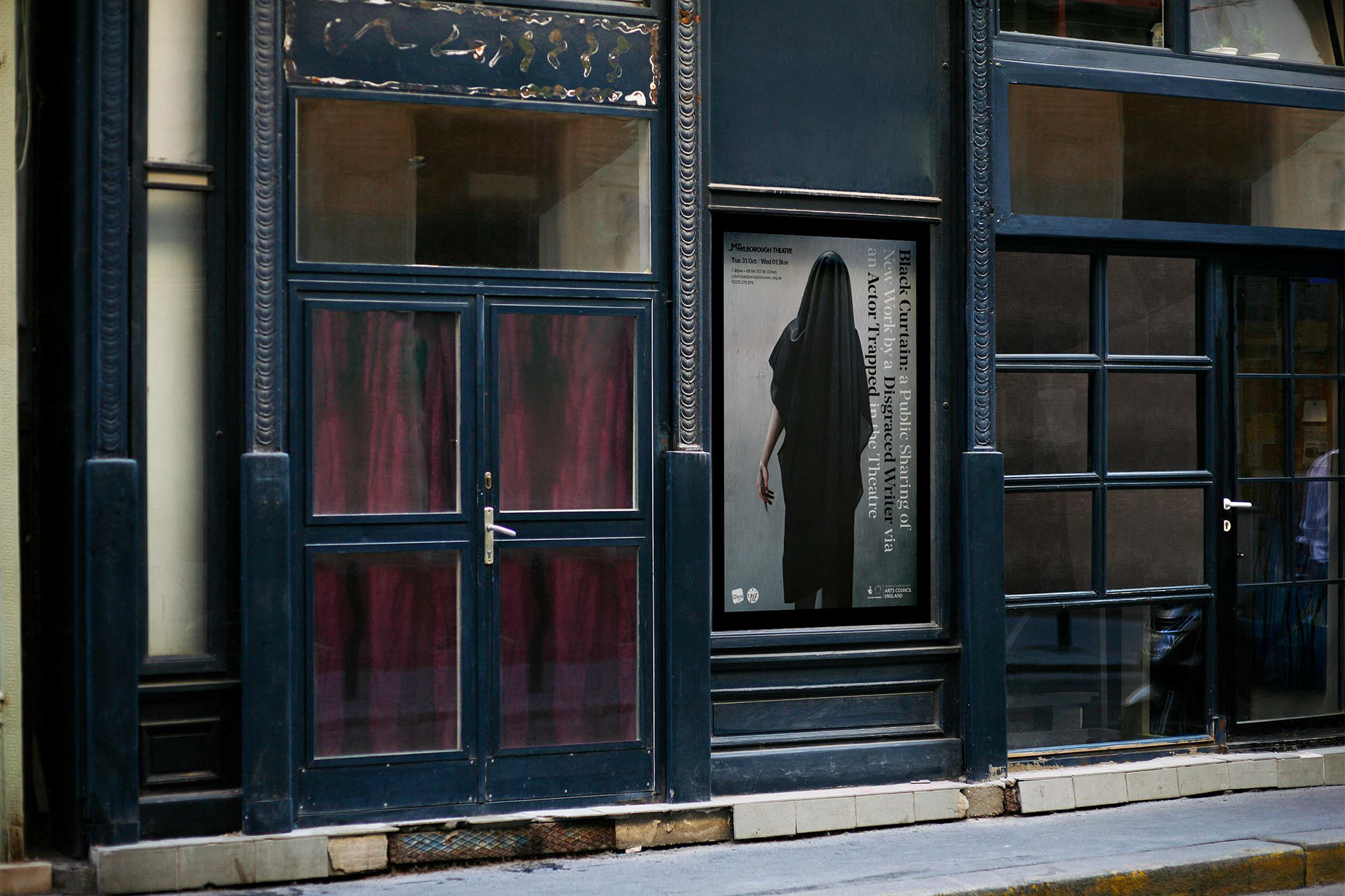 The front of an old theatre building with the Black Curtain poster framed next to the entrance
