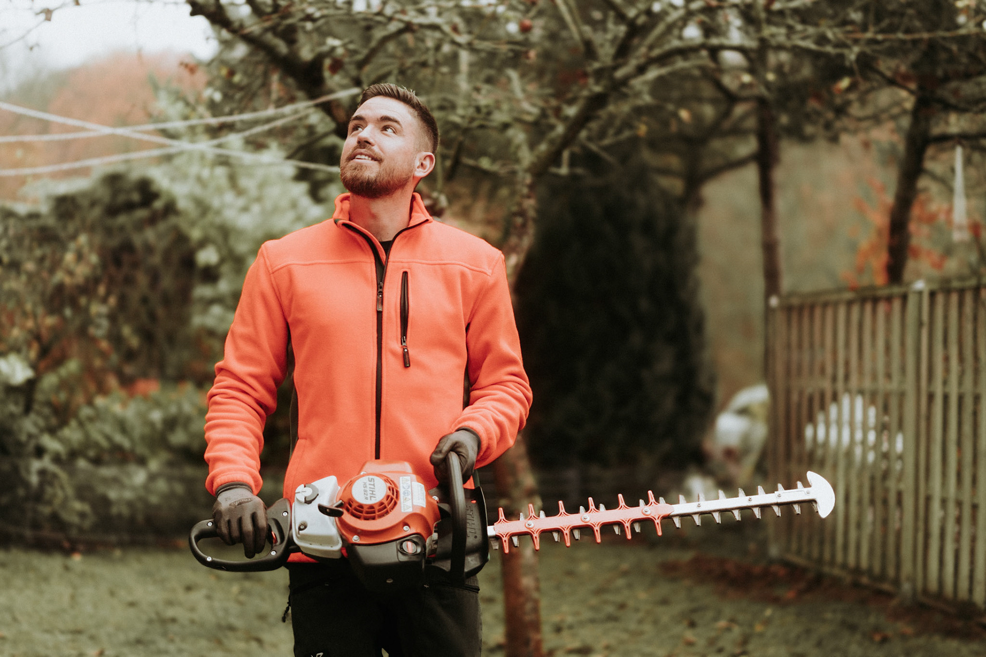 Gärtner verwendet Stihl HS 82 R Heckenschere für präzisen Heckenschnitt in einem gepflegten Garten.