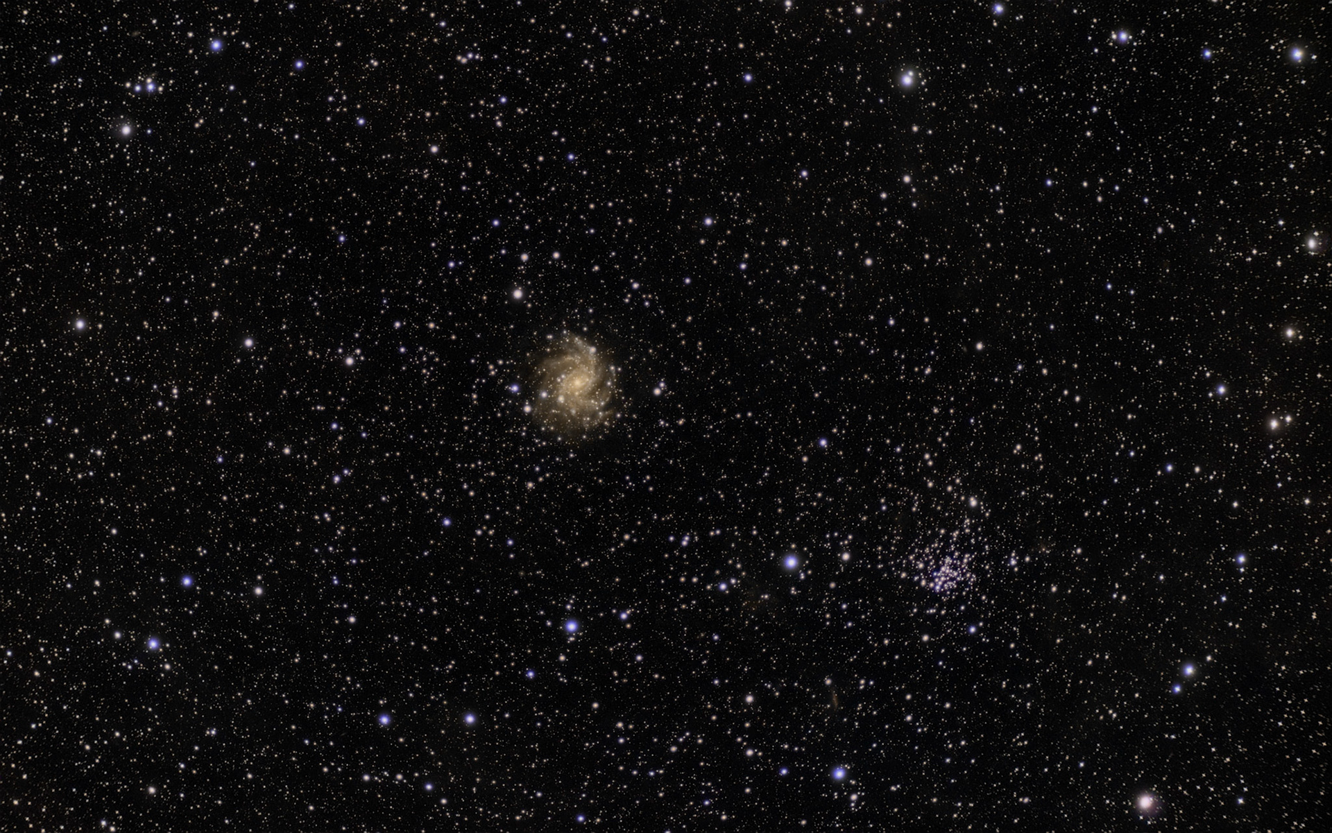 Galaxen NGC6946 (Fireworks galaxy) och stjärnhopen NGC6939 bildar ett strävsamt par på natthimlen. Galaxen ligger dock 25 miljoner ljusår bort medans stjärnhopen håller till på blott några tusen ljusårs avstånd, alltså nästan granngårds i vår egen arm av Vintergatan.