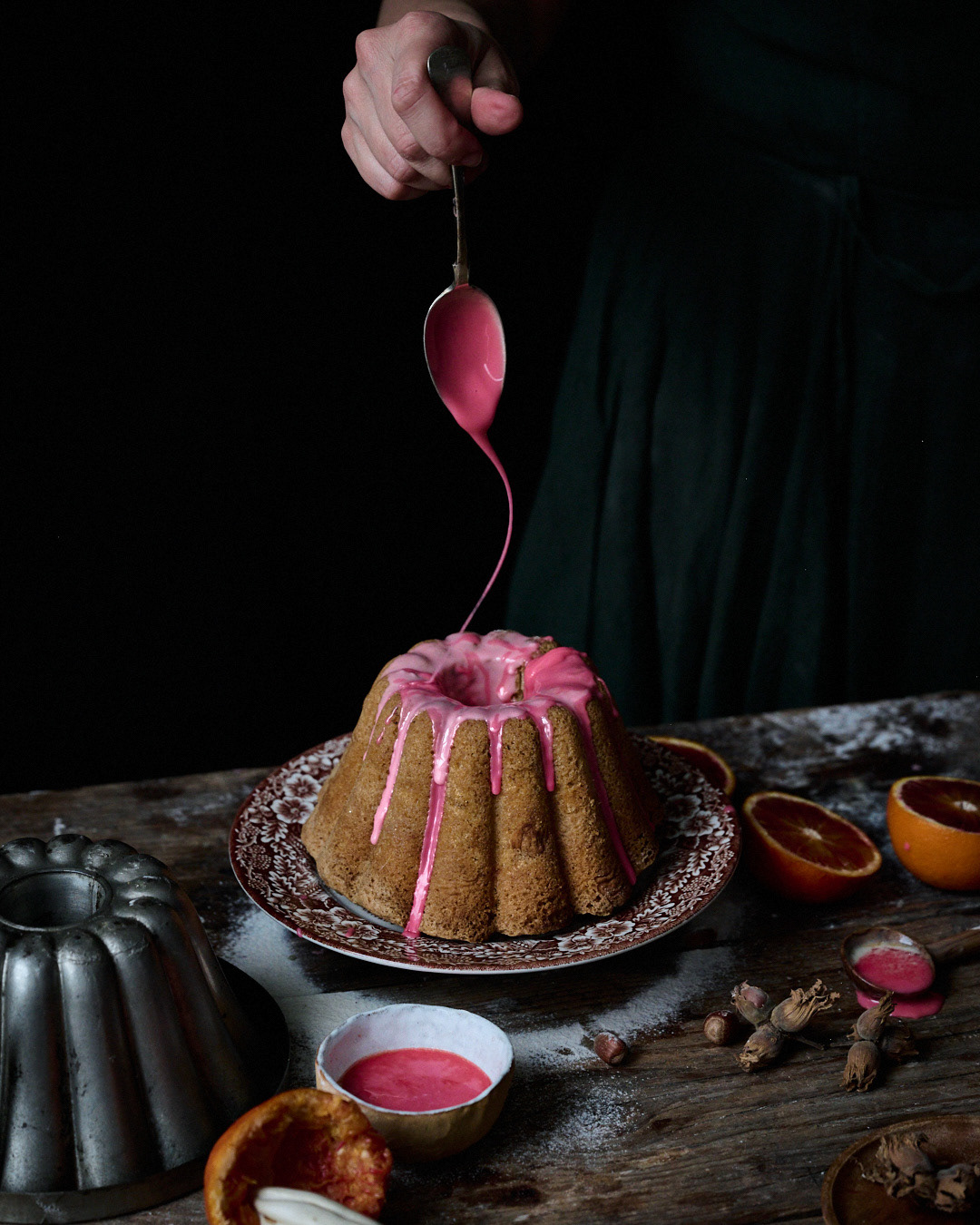 A food photography image of a bundt cake with a glorious pink icing being drizzle over the top captured by Anusha Stewart