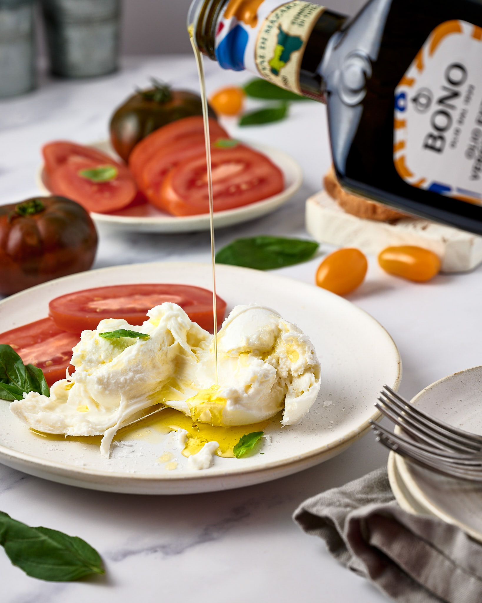 Anusha Stewart Media's image of a tomato and burrata salad being drizzled with some olive oil is wonderful