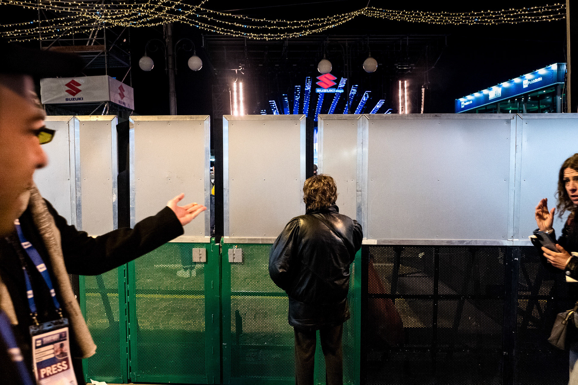 Una signora spia tra i pannelli installati nella zona nord di piazza Colombo per evitare l’ingorgo durante gli eventi presso il Suzuki Stage.