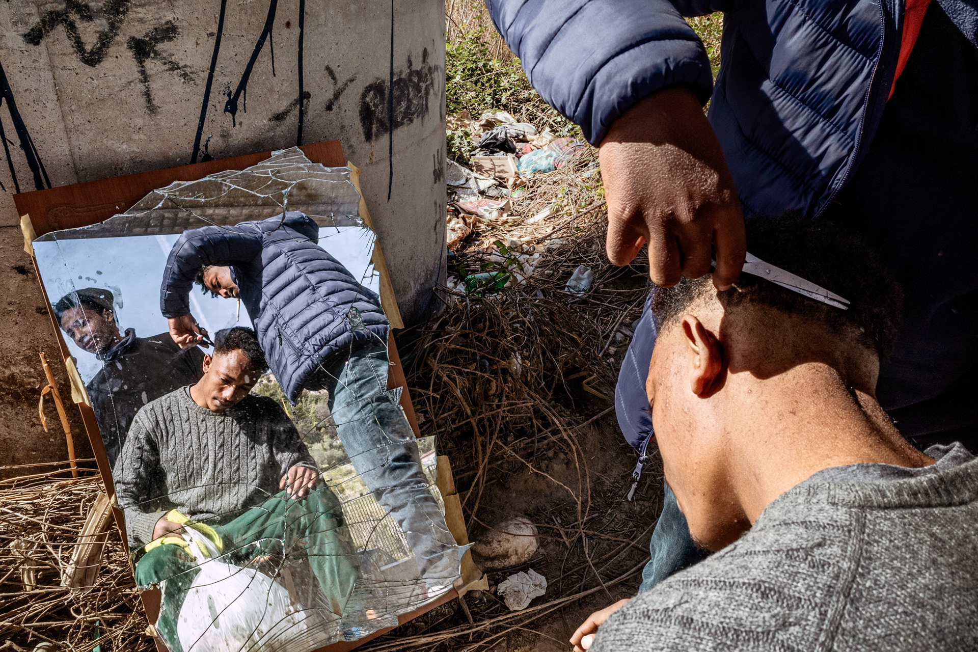 Despite the difficult hygienic and sanitary conditions and absolute poverty in which they find themselves in, care for personal appearance is not neglected, at least in the youngest trying to give themselves a semblance of dignity. The boy with scissors pictured in the photo was a professional barber in Ethiopia, his home country.