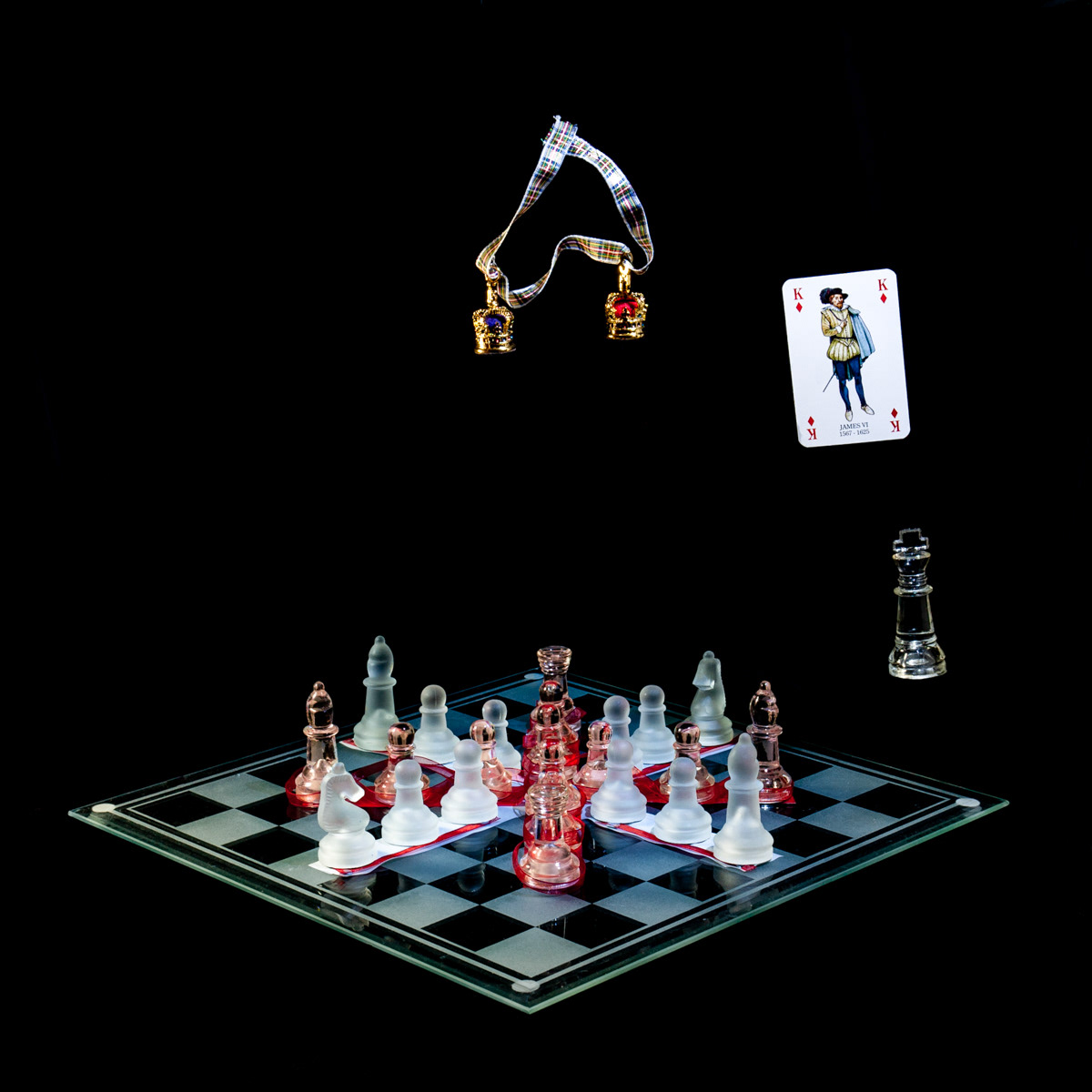 Photographic art that tells the story of King James VI inheriting the English throne, uniting the crowns of Scotland and England, using a chessboard, playing card and objects.