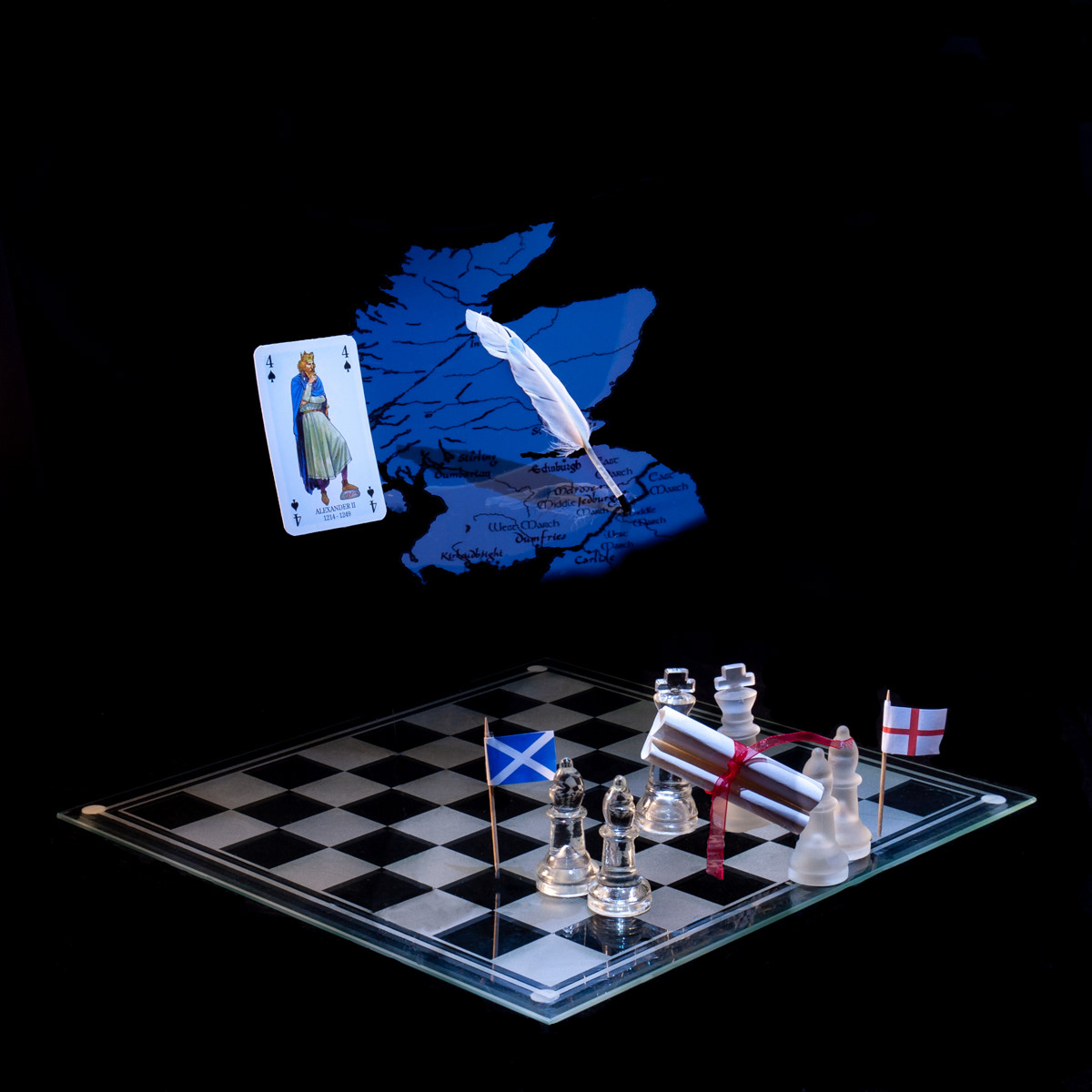 Photographic art that tells the story of King Alexander II signing a treaty that defined the Scottish English border, using a chessboard, playing card and objects.