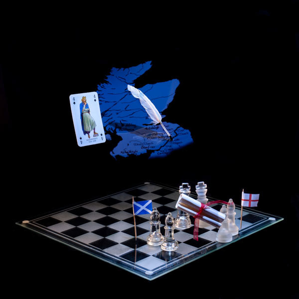 Photographic art print with image of a playing card featuring King Alexander the II, a graphic of map of Scotland and a quill floating above a chessboard with the flags of Scotland and England either side of two king pieces holding a scroll.
