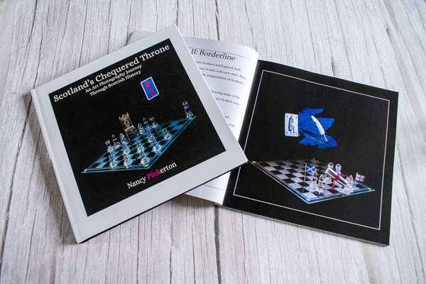 Photo of Scotland's chequered Throne book cover on top of book opened to an image showing a map of Scotland playing card hovering above a chessboard.