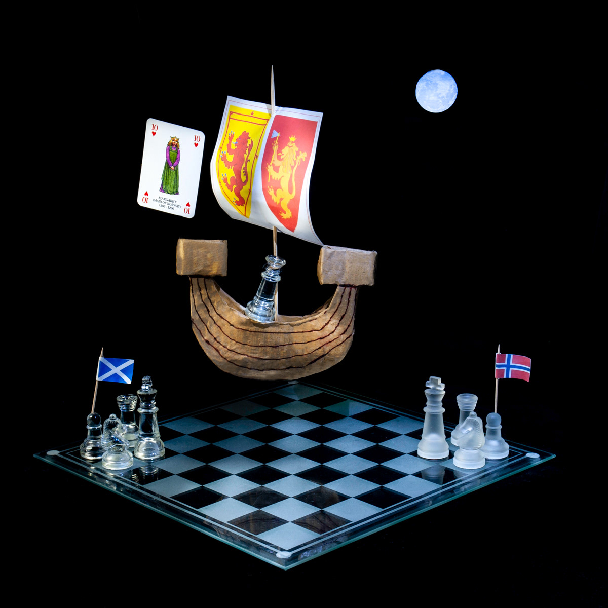 Photographic art that tells the story of Margaret the Maid of Norway's voyage to Scotland to take her place as Queen, using a chessboard, playing card and objects.
