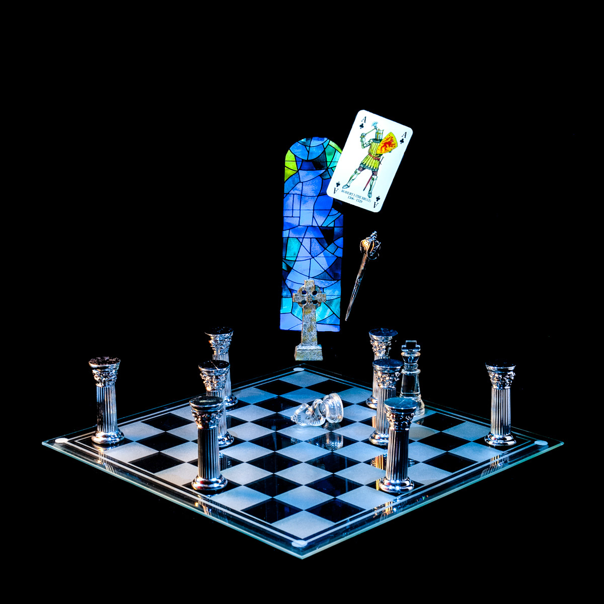 Photographic art that tells the story of a meeting that ended with Robert Bruce killing his rival for the Scottish throne, using a chessboard, playing card and objects.
