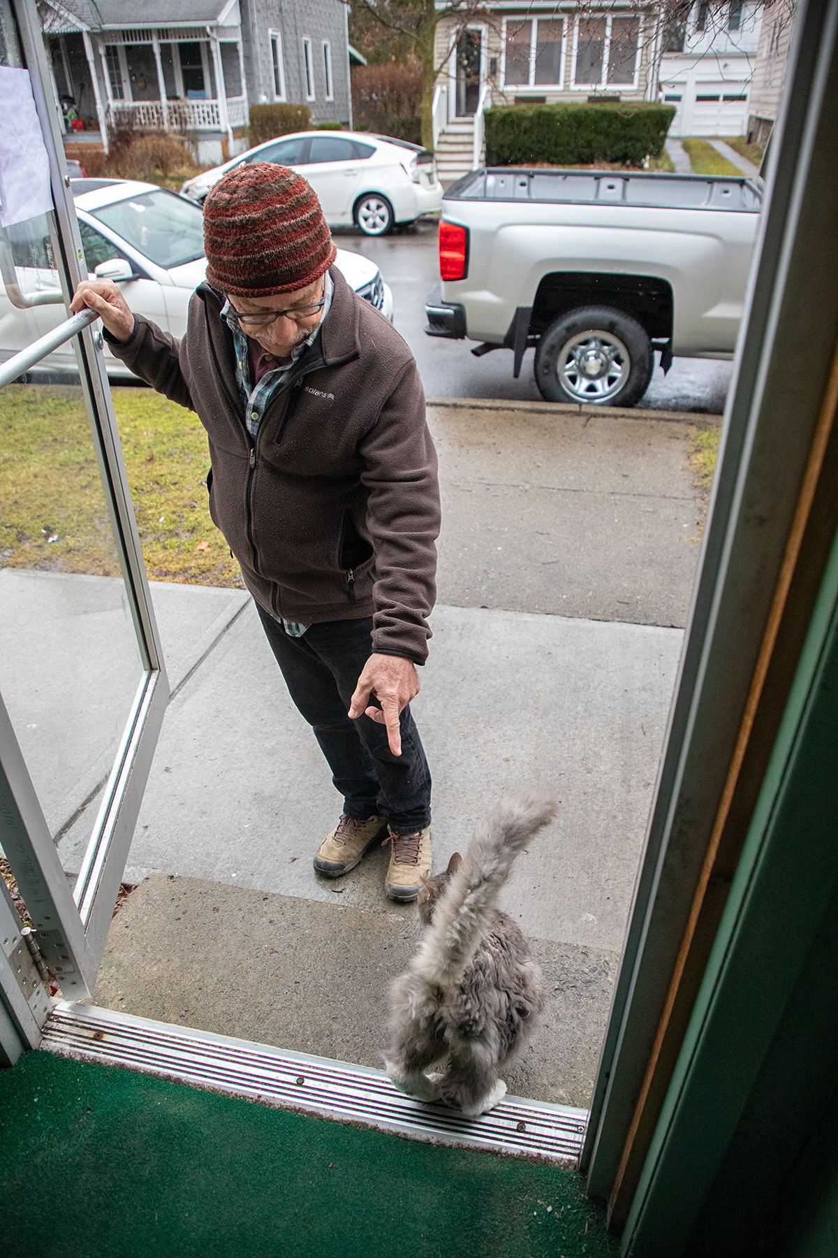 Ithaca resident Gary points down and opens the door for the cat Wednesday, Mar. 6, 2024 at Lincoln Street Diner, Ithaca, NY. Gary, who prefer not to share the last name, has been a customer at Lincoln Street Diner for 16 years. Photo by Xinyi Qin.