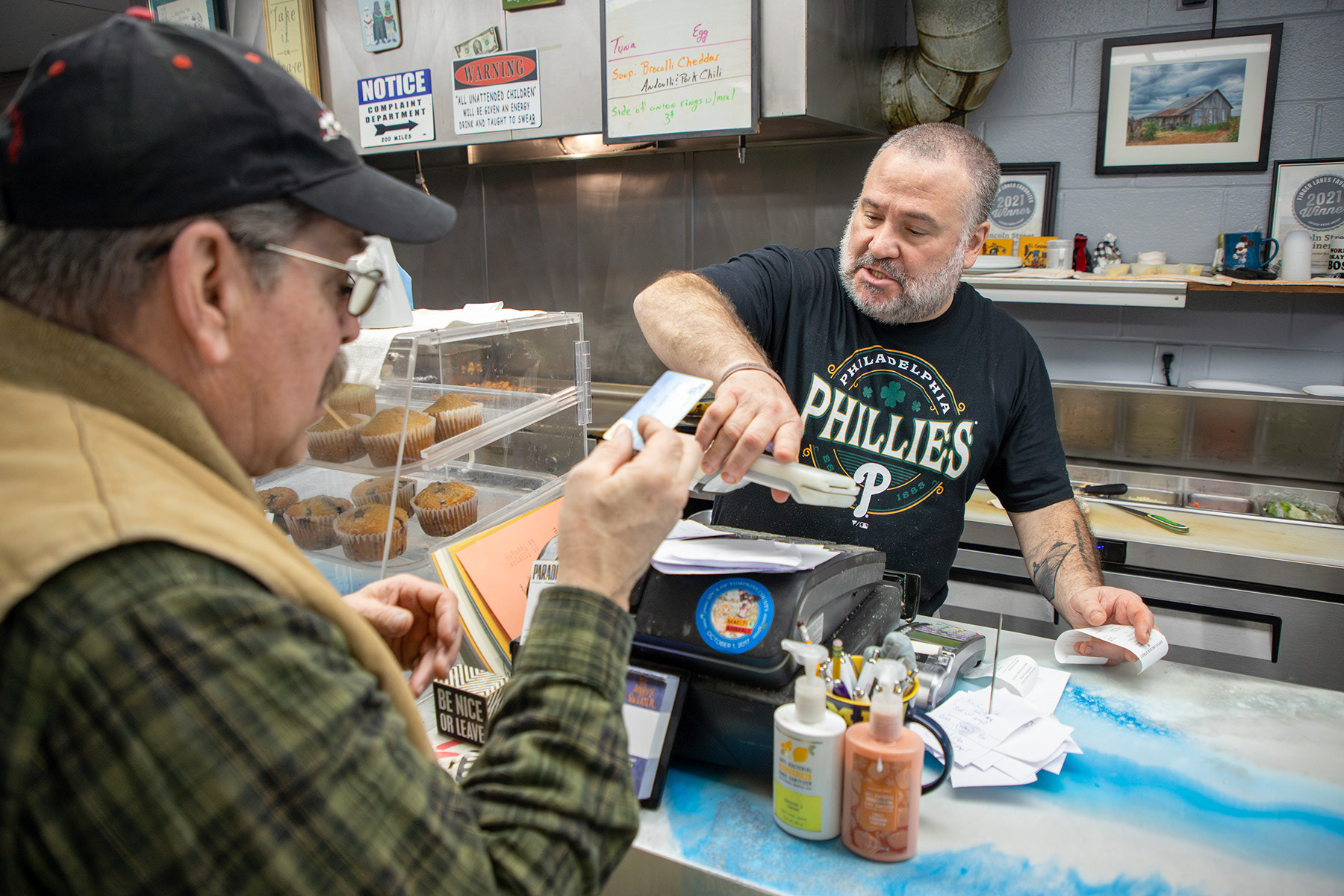 Business owner Christopher O'brien brings the bill to the customer Wednesday, Mar. 6, 2024 at Lincoln Street Diner, Ithaca, NY. Photo by Xinyi Qin.