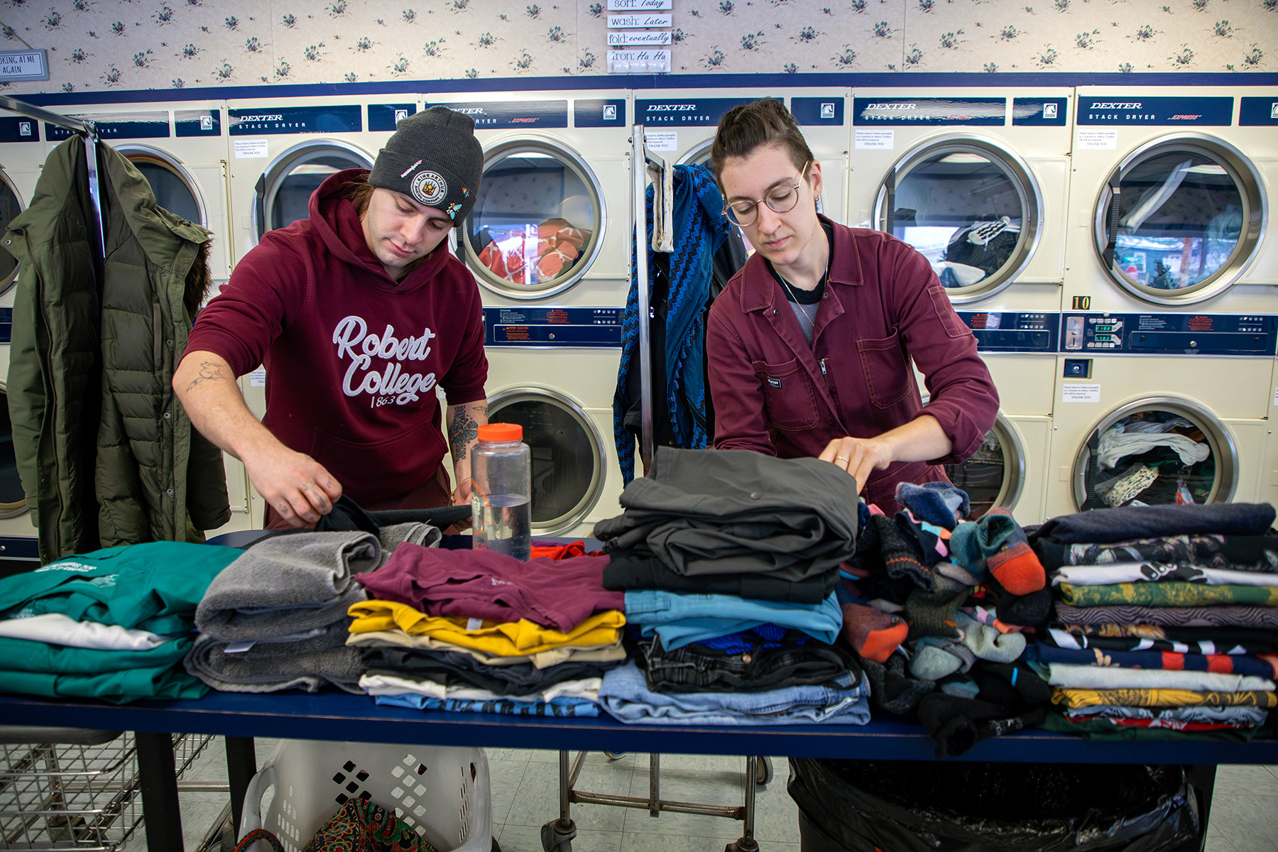 From left Lis Meiss, a registered nursing student at Jamestown Community College, and software programmer Miles Hilton fold laundry clothes Saturday, Feb. 17, 2024 at Fall Creek Laundromat, Ithaca, NY. Meiss and Hilton drives from Jamestown, NY to explore and look for potential housing in Ithaca, NY. Photo by Xinyi Qin.