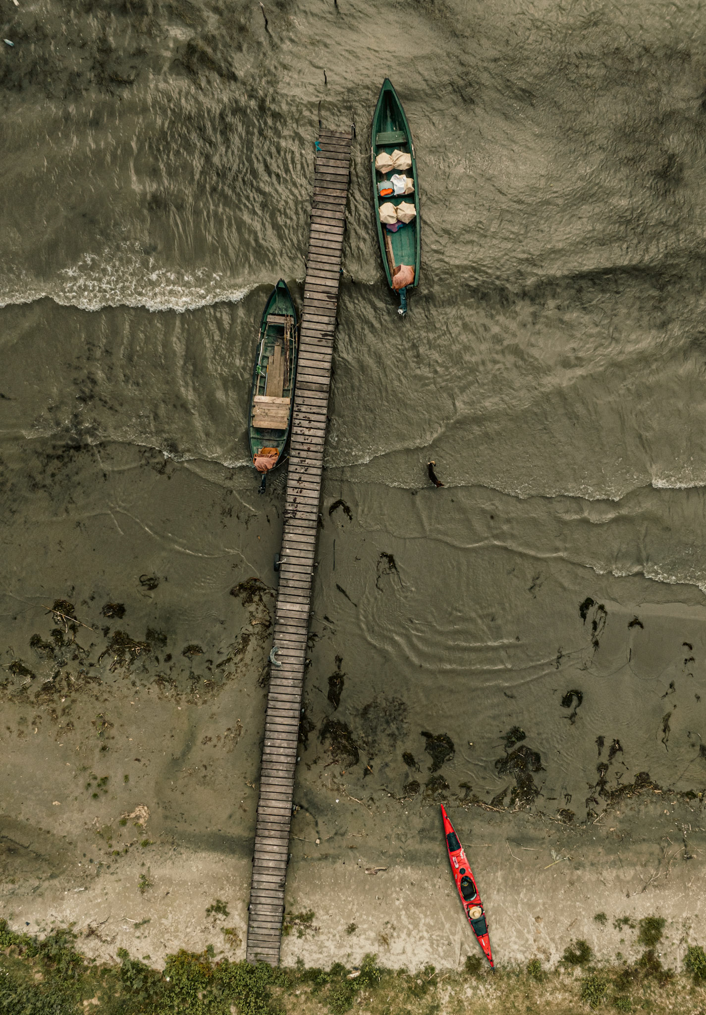 two green boats and one red kayak