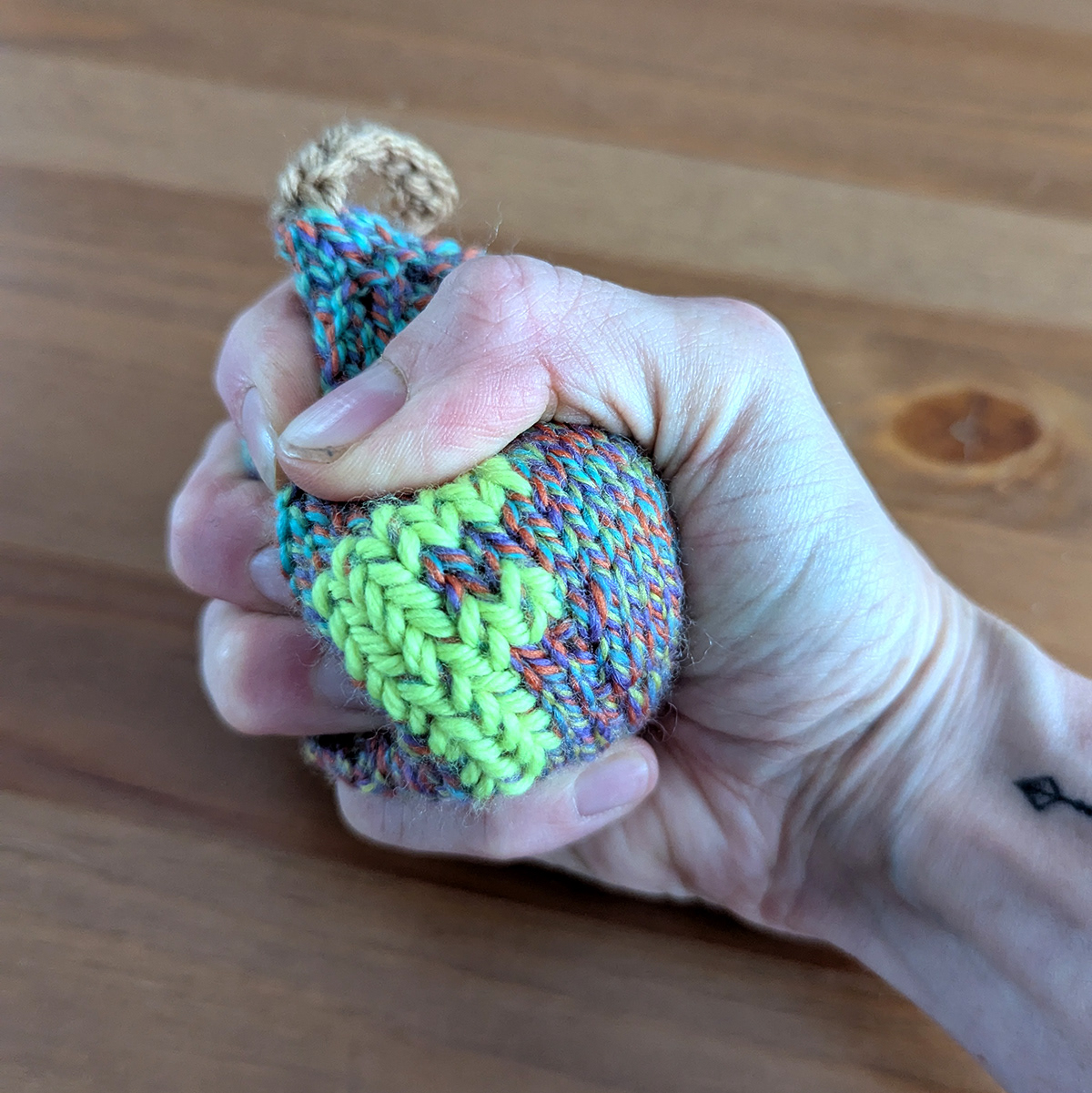 Knitted bomb being squished by a hand 