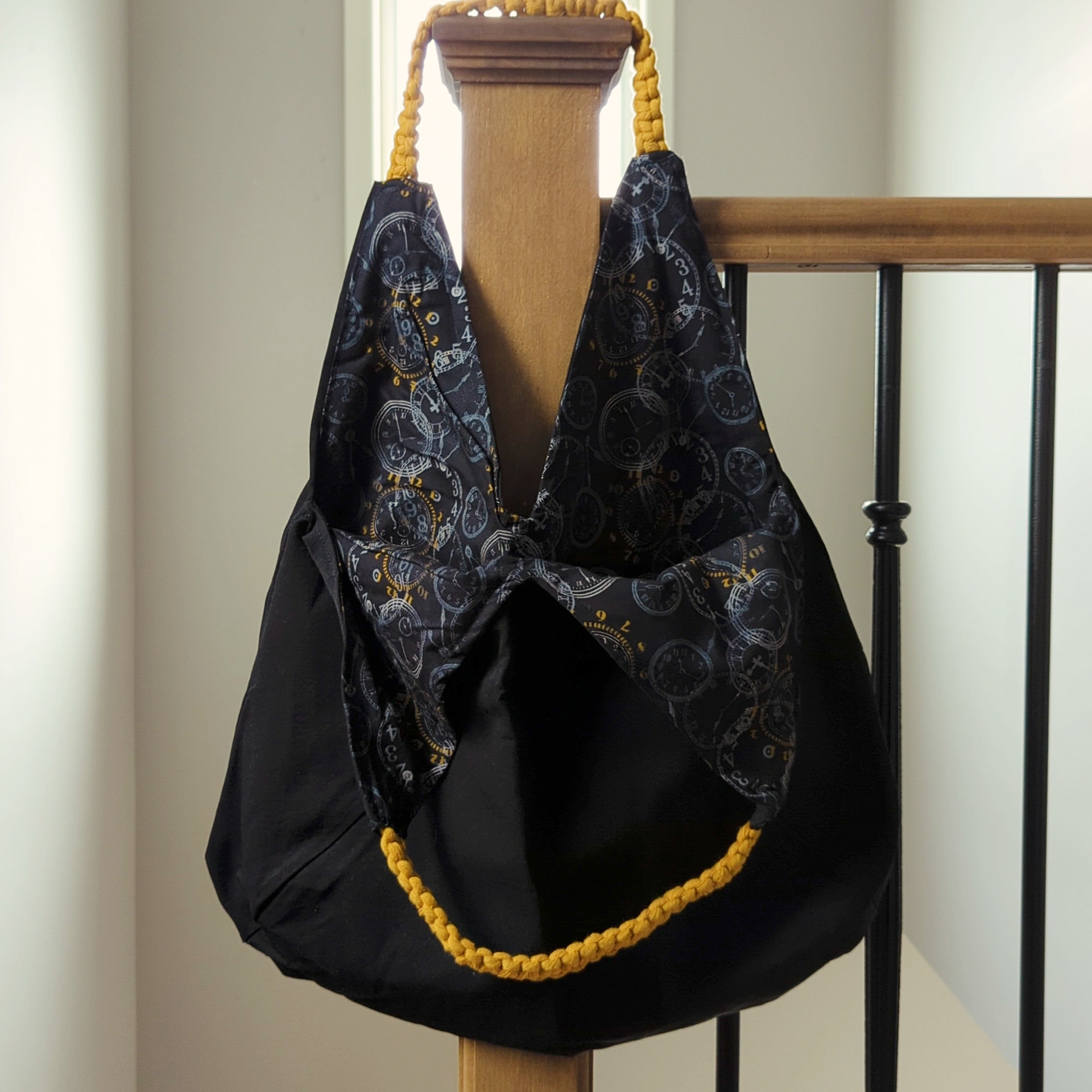 Black bag with analog clock pattern interior and yellow macrame straps
