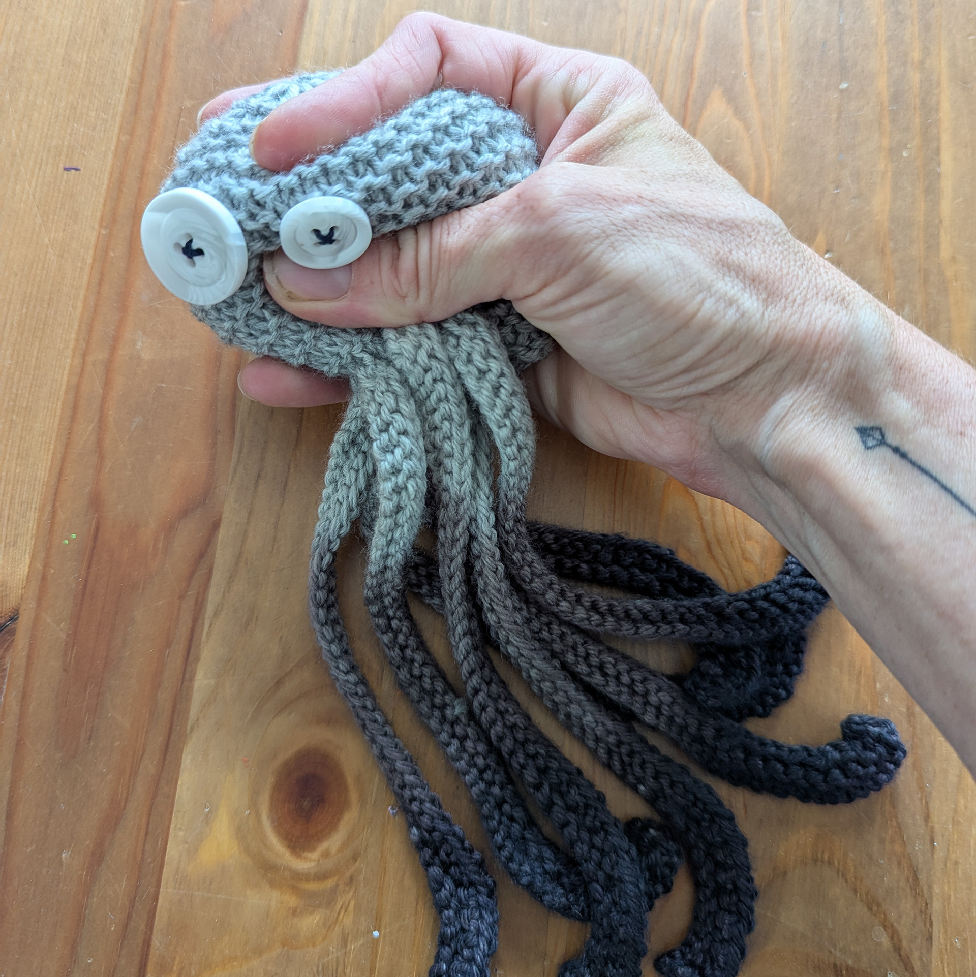 Hand knit octopus being squished by a hand