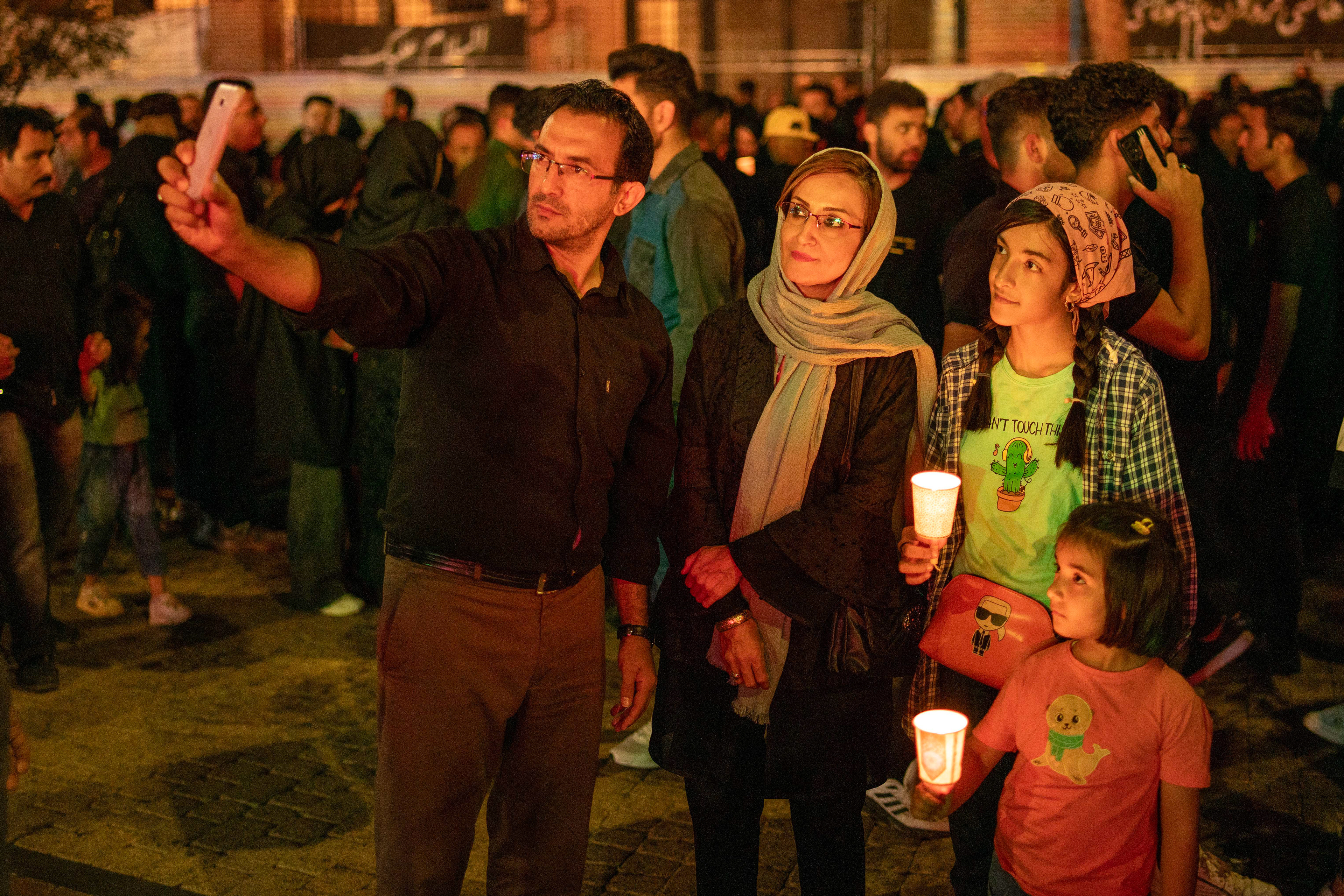 A view of a family taking a selfie with their mobile phone in Ardabil. Shiite Muslims light candles to be a light for Imam Hussein on the Day of Ashura, unique to the city of Ardabil.