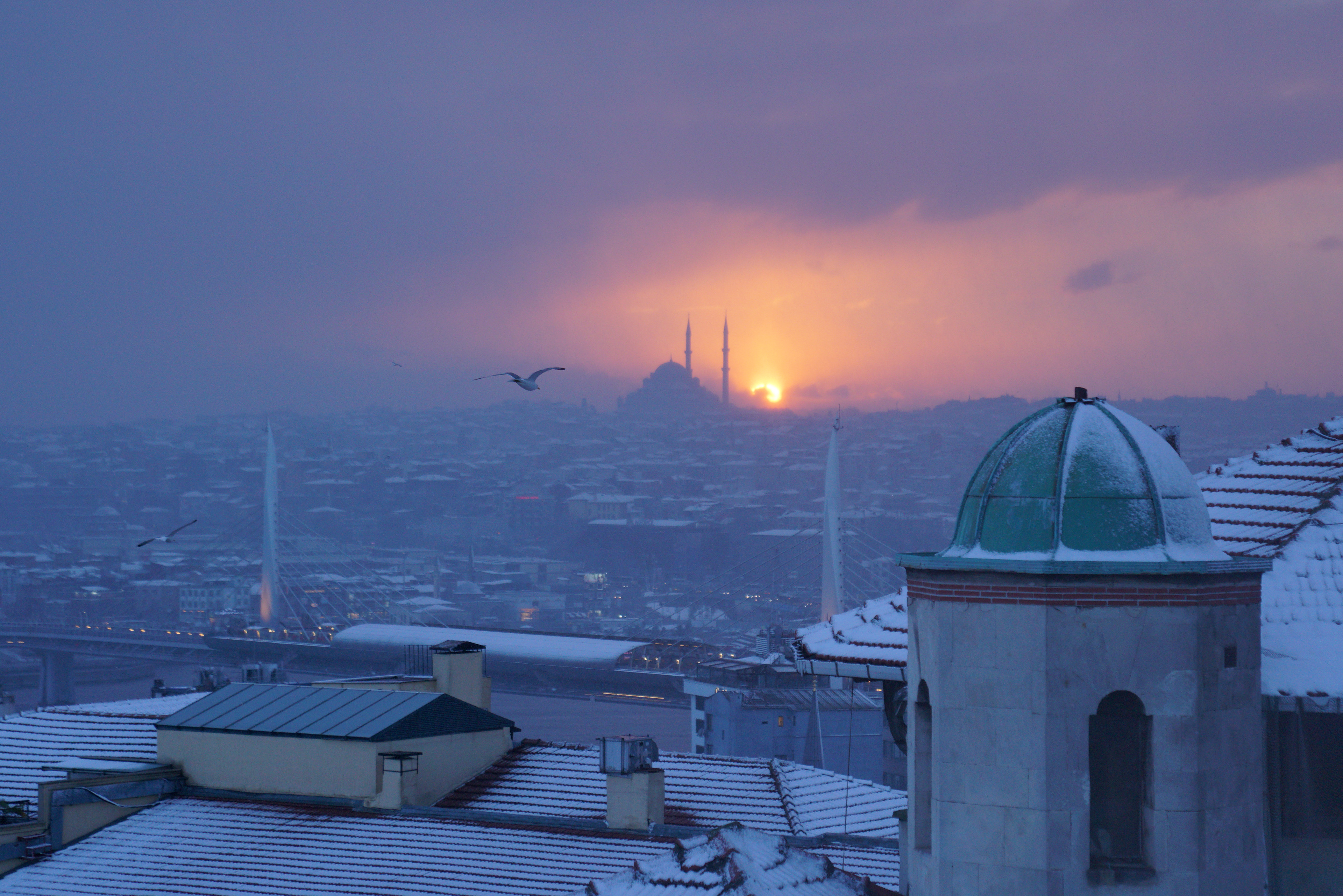 General view of Fatih district, a historical peninsula, as the sun sets behind the Fatih Mosque, background, under heavy snowfall in Istanbul, Turkey on February 21, 2025.