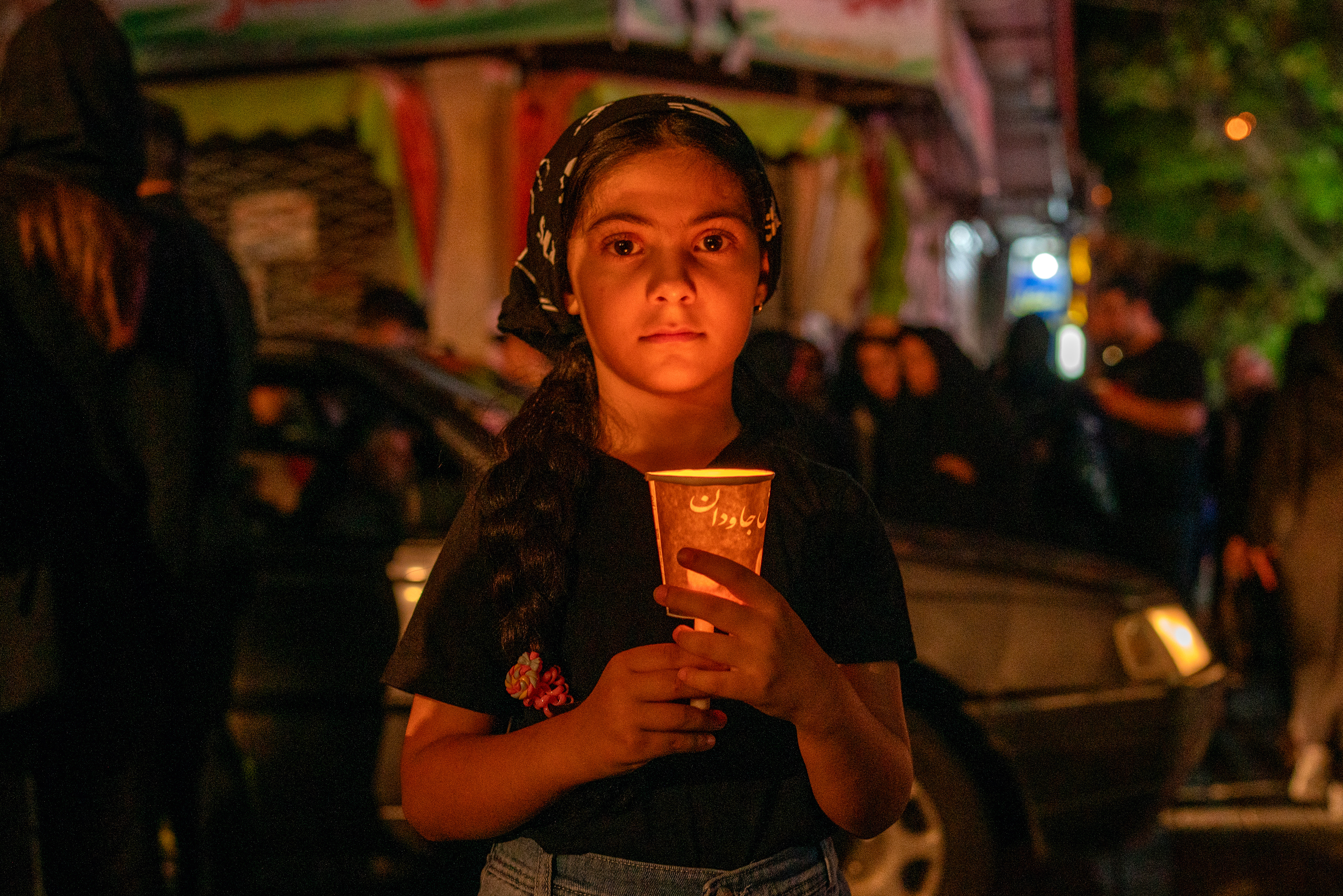A young girl, in Tabriz, Iran on July 27, 2023, lights a candle to bring 'a light for Imam Hussein' at the Tasua commemoration, the 1384th anniversary of the martyrdom of Imam Hussein, the grandson of the Islamic Prophet Muhammad, and 72 of his companions in Karbala.