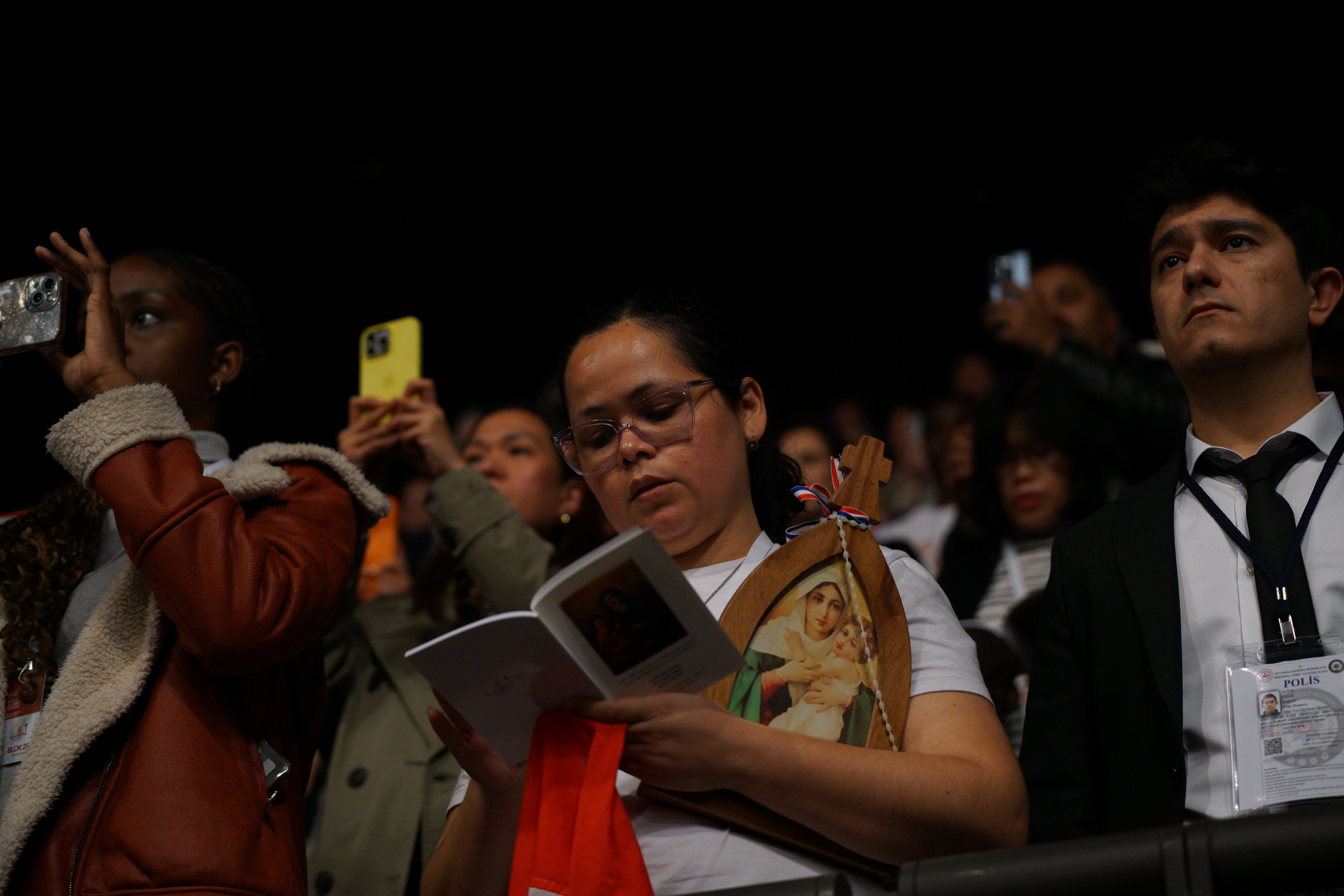 Faithfuls pray and take photos as Pope Leo XIV celebrates a Mass at the Volkswagen Arena in Istanbul, during his first apostolic journey, on November 29, 2025.