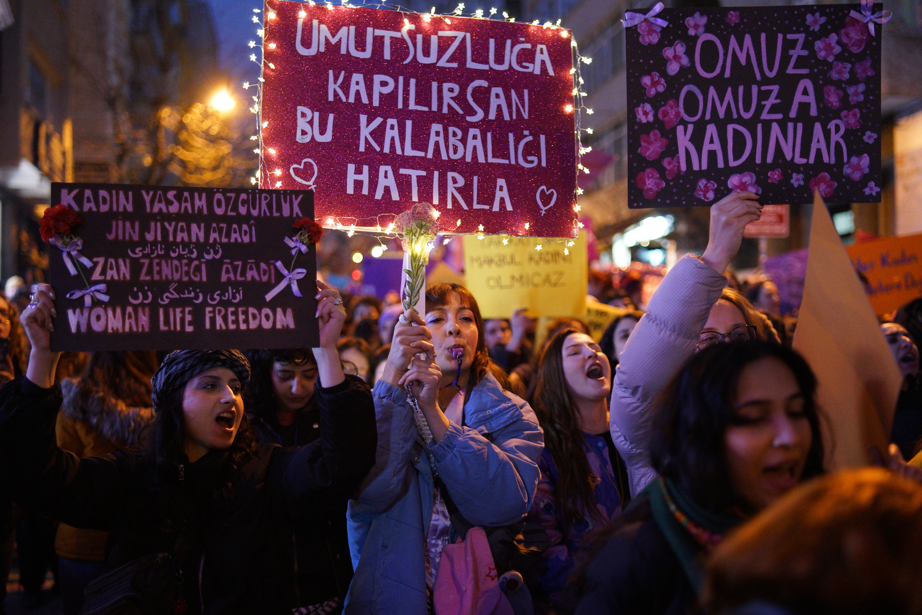 Women hold placards during a march marking International Women's Day near Taksim Square, in Istanbul on March 8, 2026.