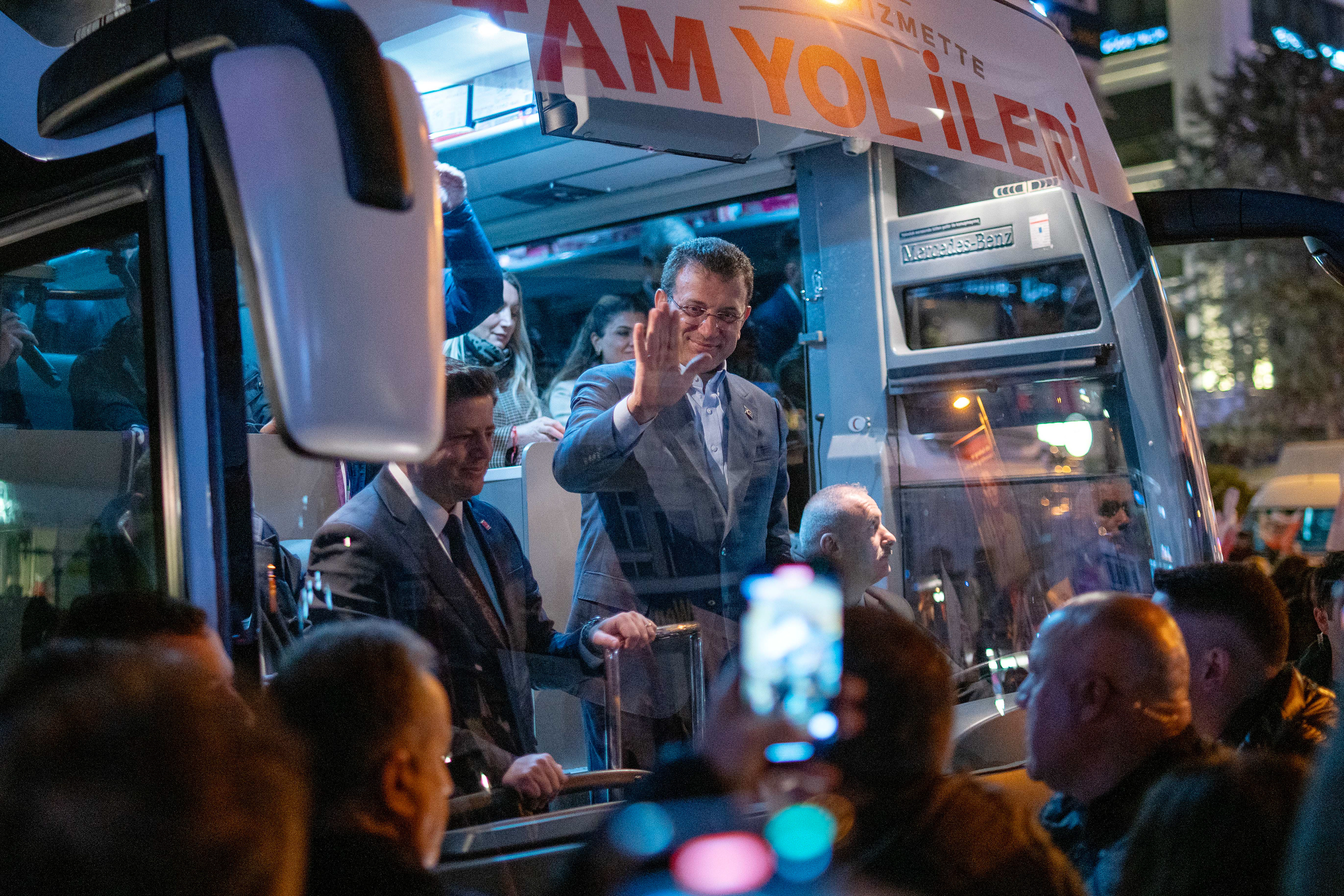 Istanbul Metropolitan Municipality Mayor and candidate Ekrem Imamoglu (C) greets the people from inside the bus while coming to the after public meeting in Kadikoy, Istanbul on March 15, 2024. 