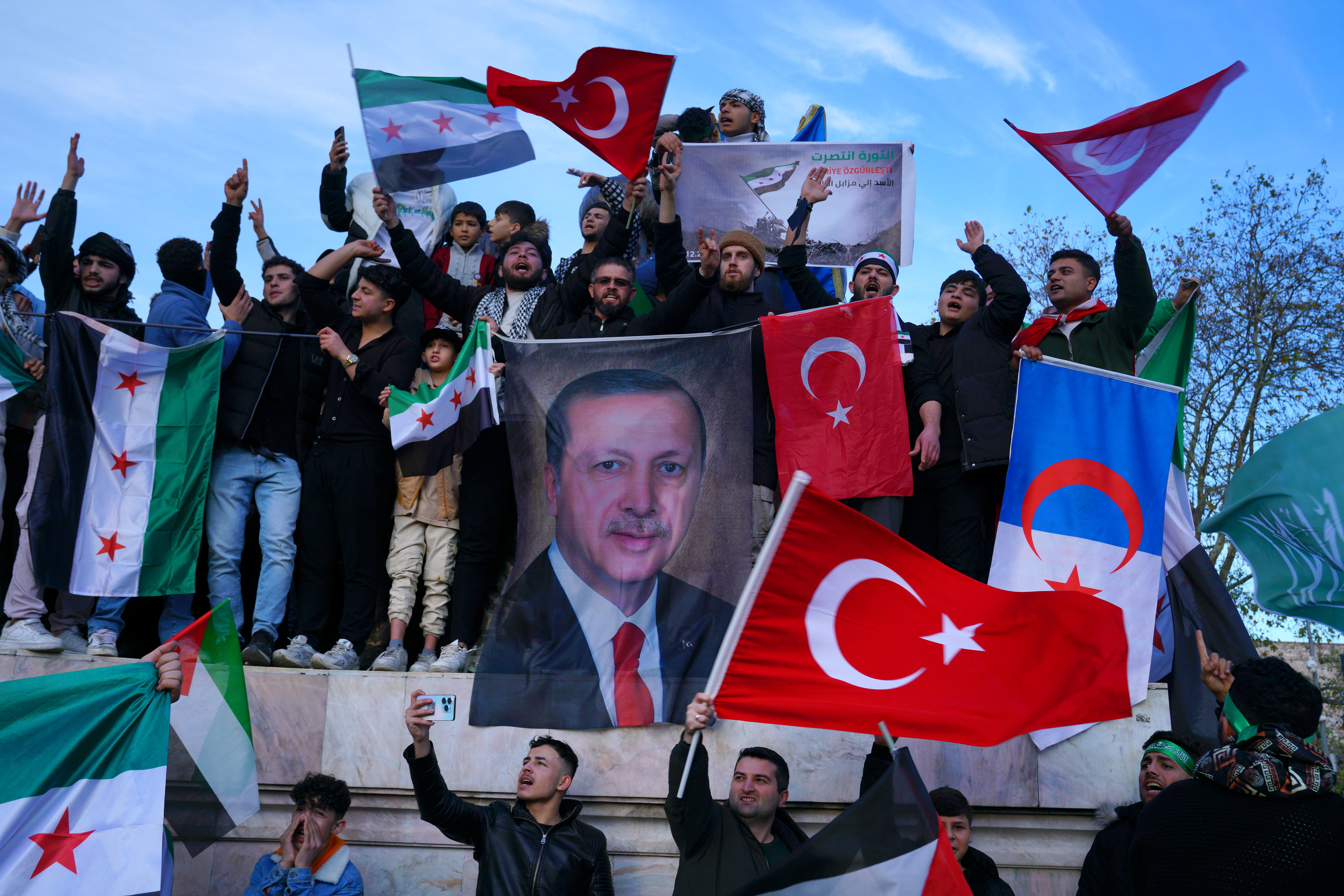 Syrians living in Turkey holding a large poster of Turkish President Recep Tayyip Erdogan after Syrian rebels announced that they have ousted President Bashar al-Assad, at Sarachane Square in Istanbul, Turkey, December 8, 2024.