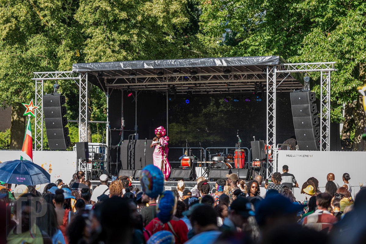 Een artiest treedt op voor het publiek tijdens het Keti Koti Festival in het Wijkpark Oude Westen, Rotterdam. · A performer takes the stage before the crowd at the Keti Koti Festival in Wijkpark Oude Westen, Rotterdam.