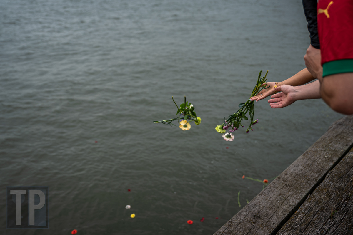 Bloemen worden in de Maas geworpen ter nagedachtenis aan de tot slaaf gemaakten die tijdens de overtocht om het leven kwamen, tijdens de bloemenceremonie bij de Keti Koti-herdenking, Rotterdam. · Flowers are cast into the Maas in remembrance of the enslaved who perished during the crossing, during the flower ceremony at the Keti Koti commemoration, Rotterdam.