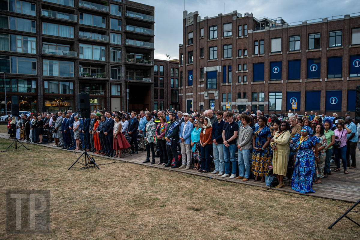 Aanwezigen staan stil tijdens de officiële Keti Koti-herdenking bij het slavernijmonument aan de Lloydkade, Rotterdam. · Attendees observe a moment of reflection during the official Keti Koti commemoration at the slavery monument on the Lloydkade, Rotterdam.