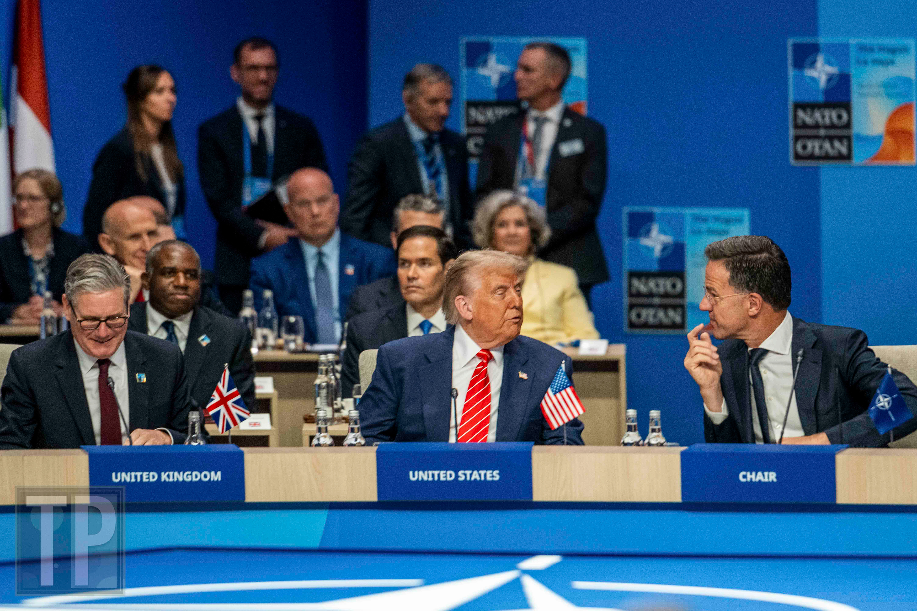 US President Donald Trump engages in a conversation with NATO Secretary General Mark Rutte, while Prime Minister of the United Kingdom Keir Starmer listens in on the exchange.