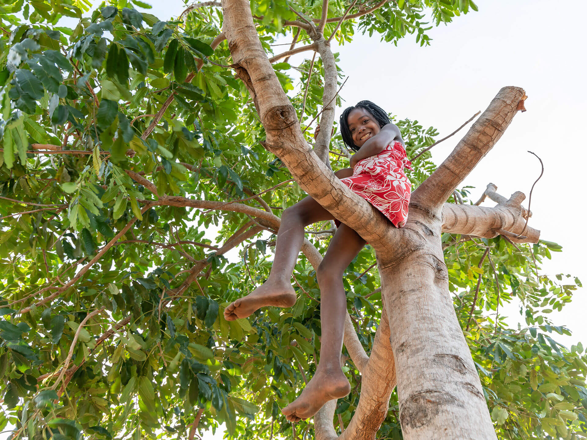 Young girl sitting on the branch of tree at Lago Matsambe, Mozambique