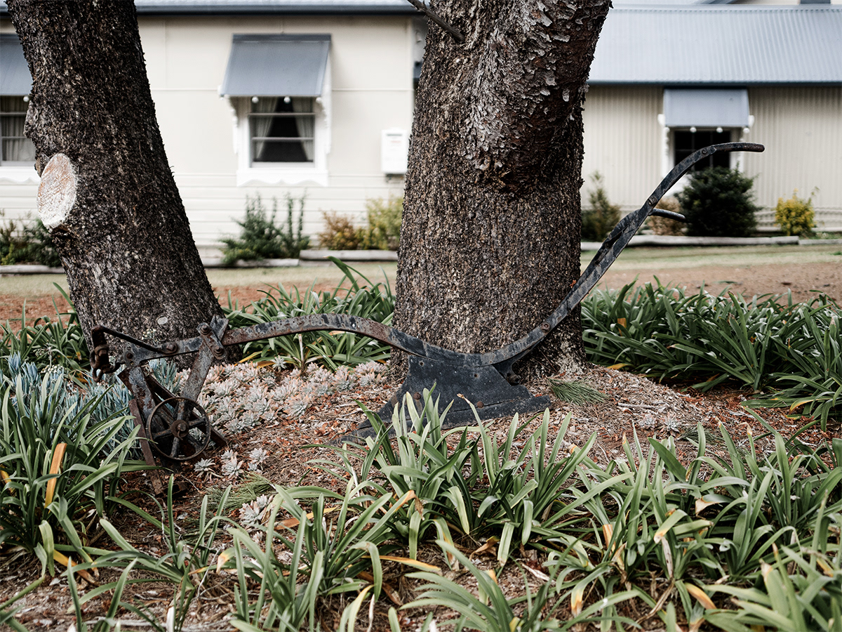 An old plough rests in the circular driveway garden