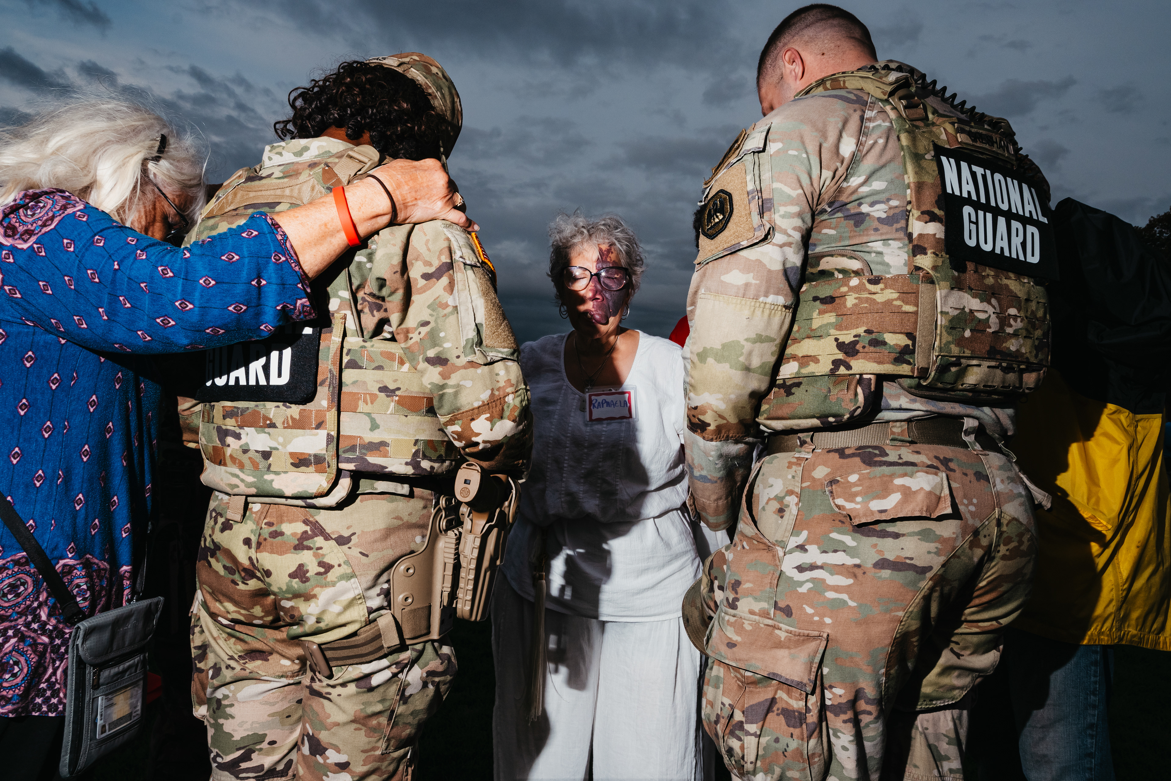 National Guardsmen being led in prayer by an event attendee.