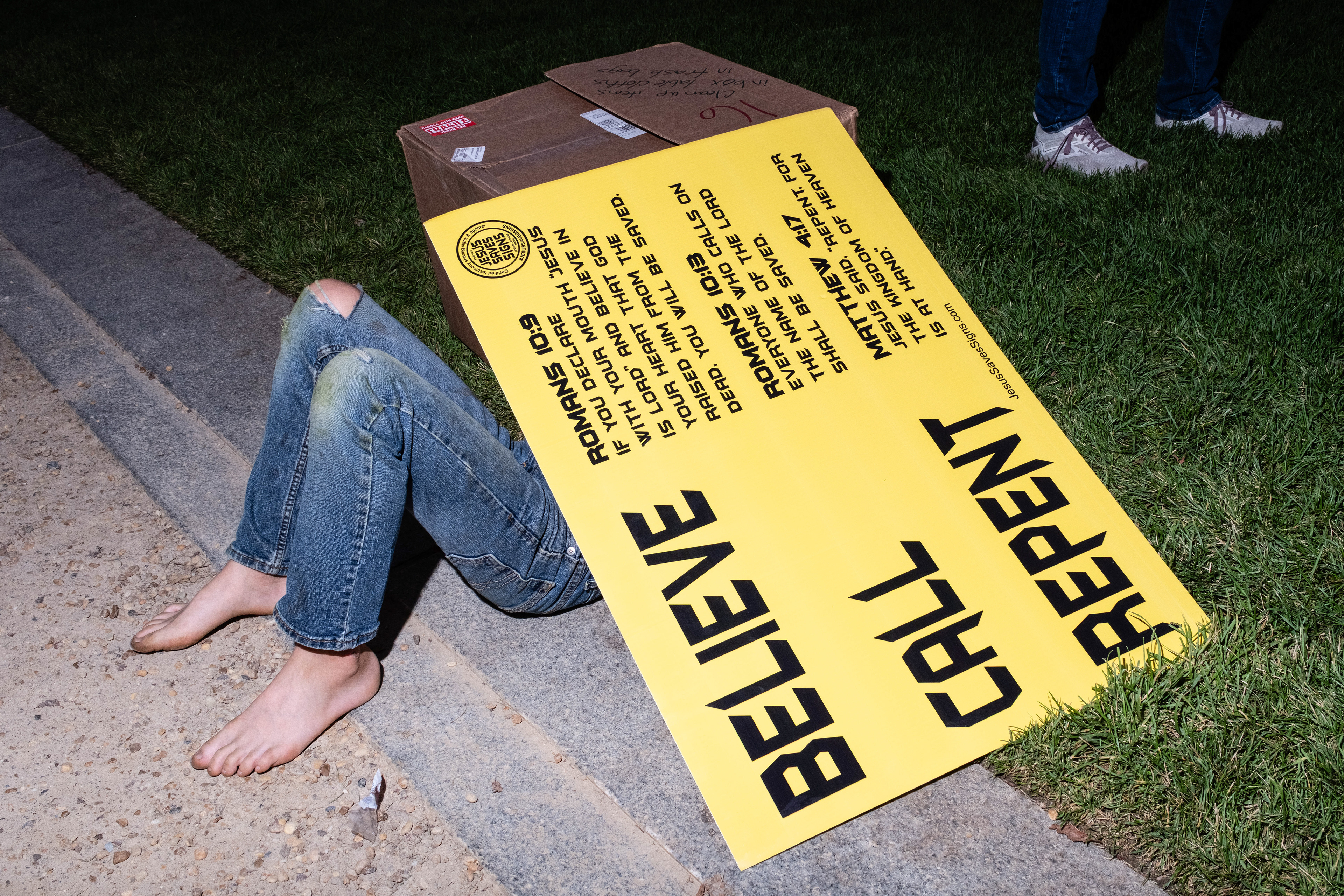 A child resting under some proselytizing signage