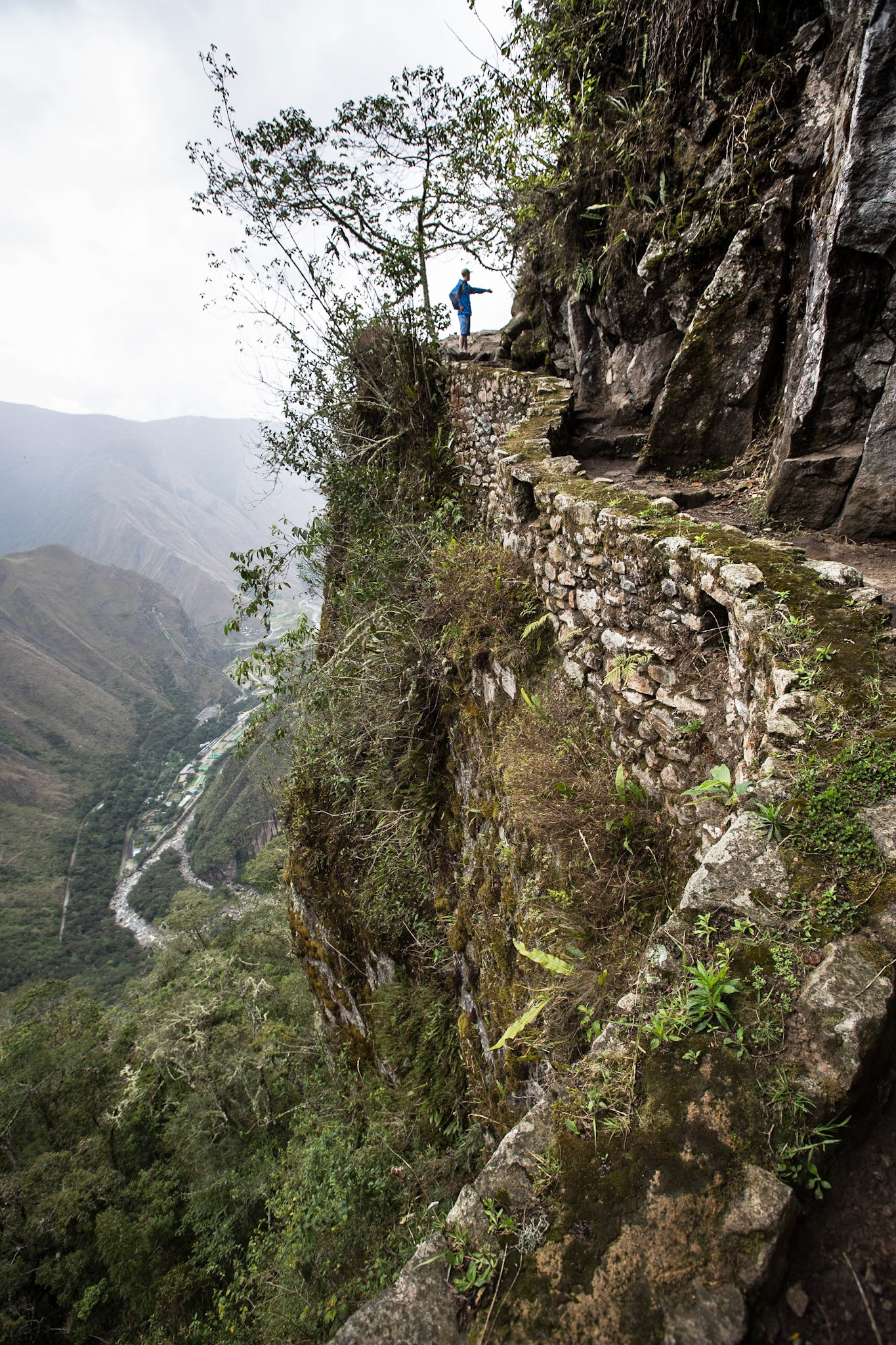 This is a mountain trail heading to the Inca Bridge, west from Machu Picchu. The trail is a stone path, part of which is cut into a cliff face.