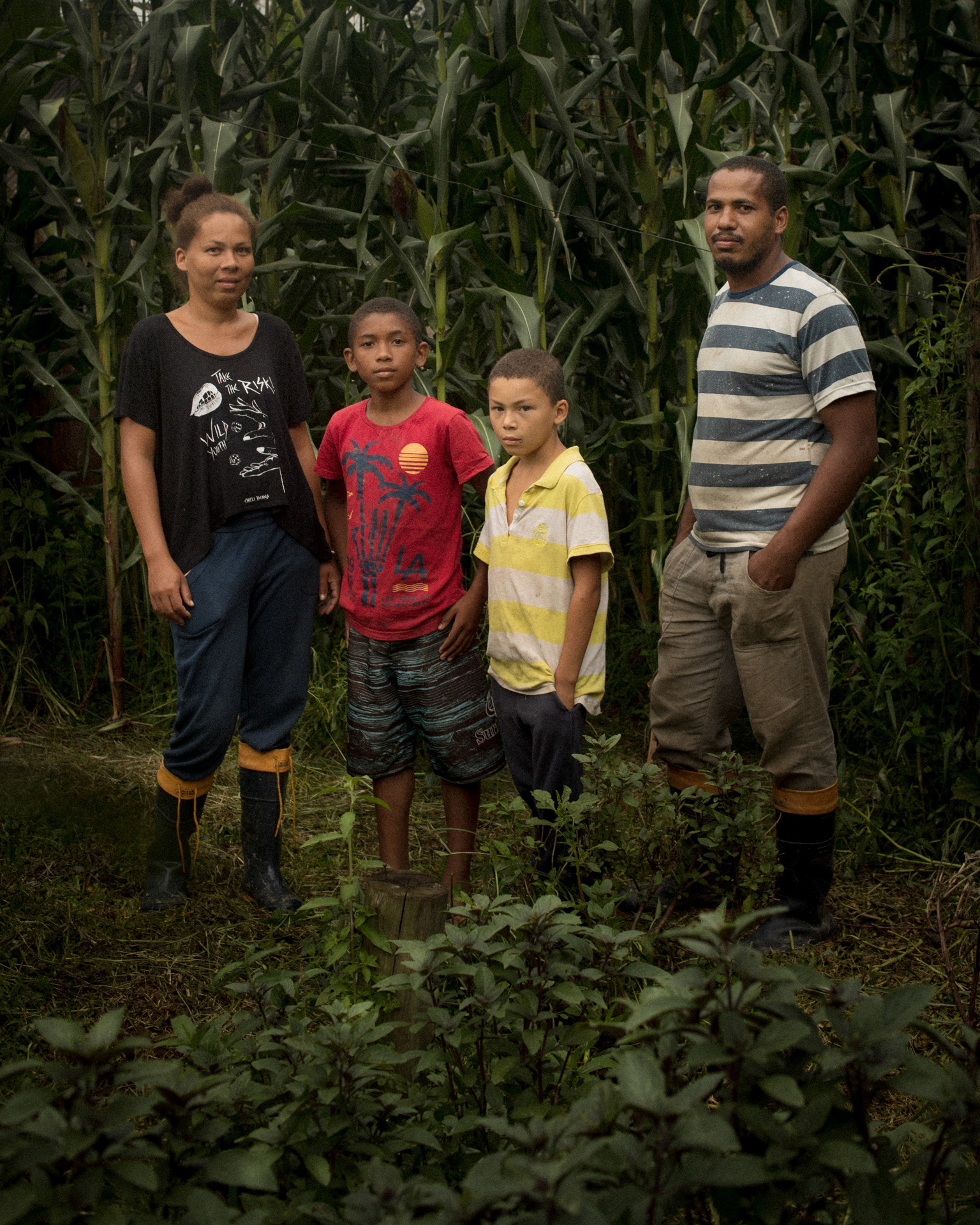 retrato de Valdemir, Maria Erivania e seus filhos, Thallyson e Kaique, uma das famílias do Assentamento Comuna Amarildo, estão em frente a uma plantação de milhos