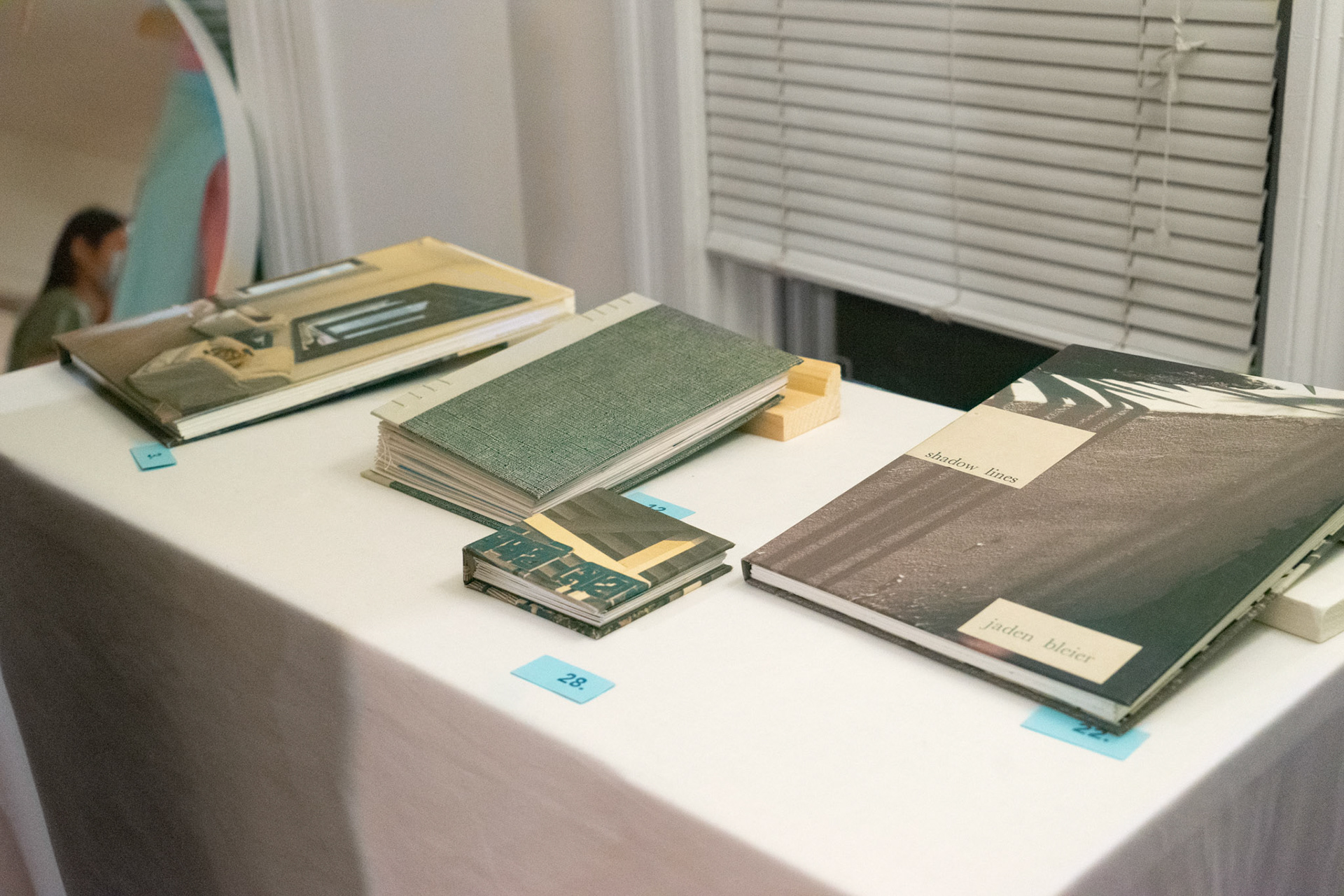 left to right: "banani house" (hand bound photo book), "im glad that i met u" (collage book) and "unfamiliar home" (book) by Areez Khan, "shadow lines" (hand-bound photo book) by Jaden Bleier (this photo by Jaden Bleier)