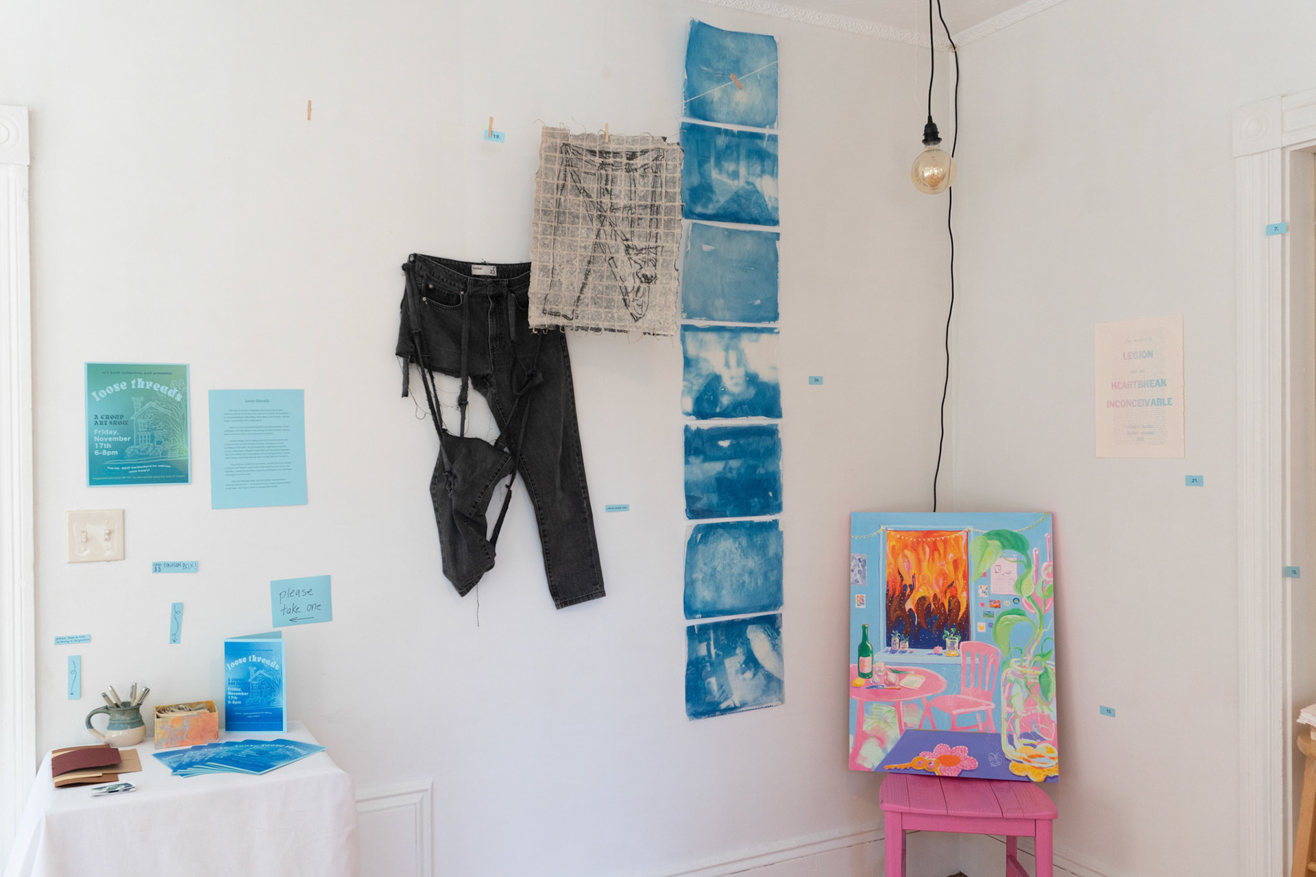 center to right: "re-repair-pair (pants weren't ripped when I bought them)" (found jeans, monotypem clothesline) and "tracing" (cyanotype on tracing paper) by Jaden Bleier, "life these days" (acrylic on canvas) by Hannah Bashkow, "Selections from Anti-Trans Legislation Passed in 23 States in 2023" (letterpress on Stonehenge) by Iris Wright