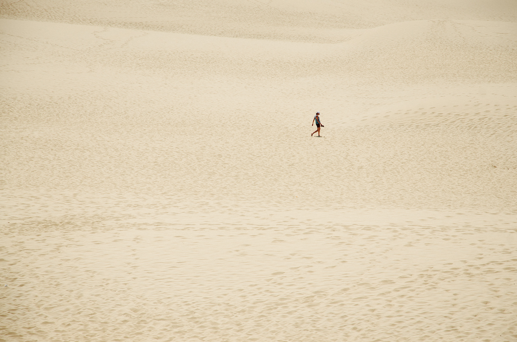 die Weite der Dune du Pilat mit einer einsamen Spaziergängerin.