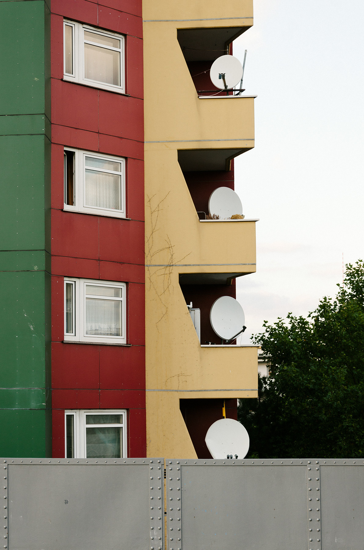 Grün, rot, gelbe Fassadenansicht mit Parabolantennen auf den Balkonen von Mehrfamilienhaus in der Prinzenstrasse, Berlin