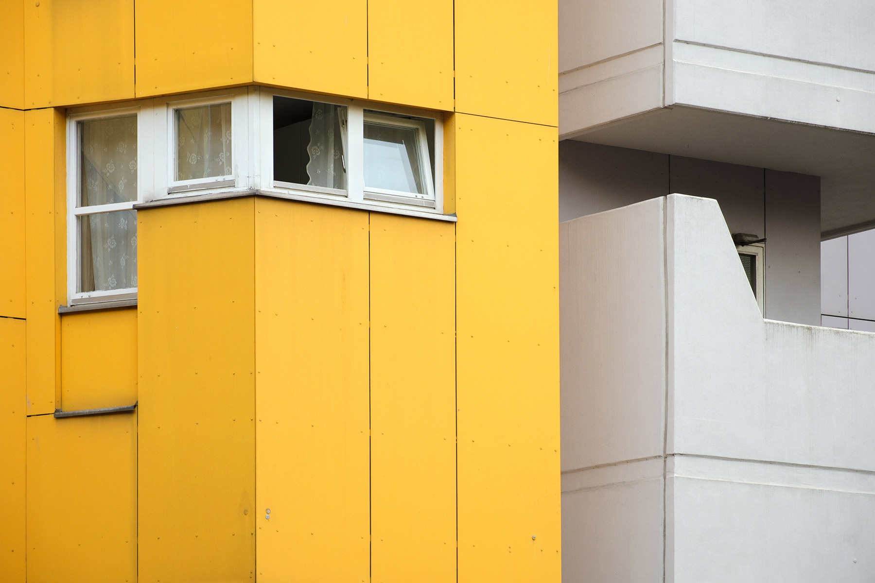 Gardine in offenem Fenster hinter gelber Fassade in Böcklerstrasse, Berlin-Kreuzberg