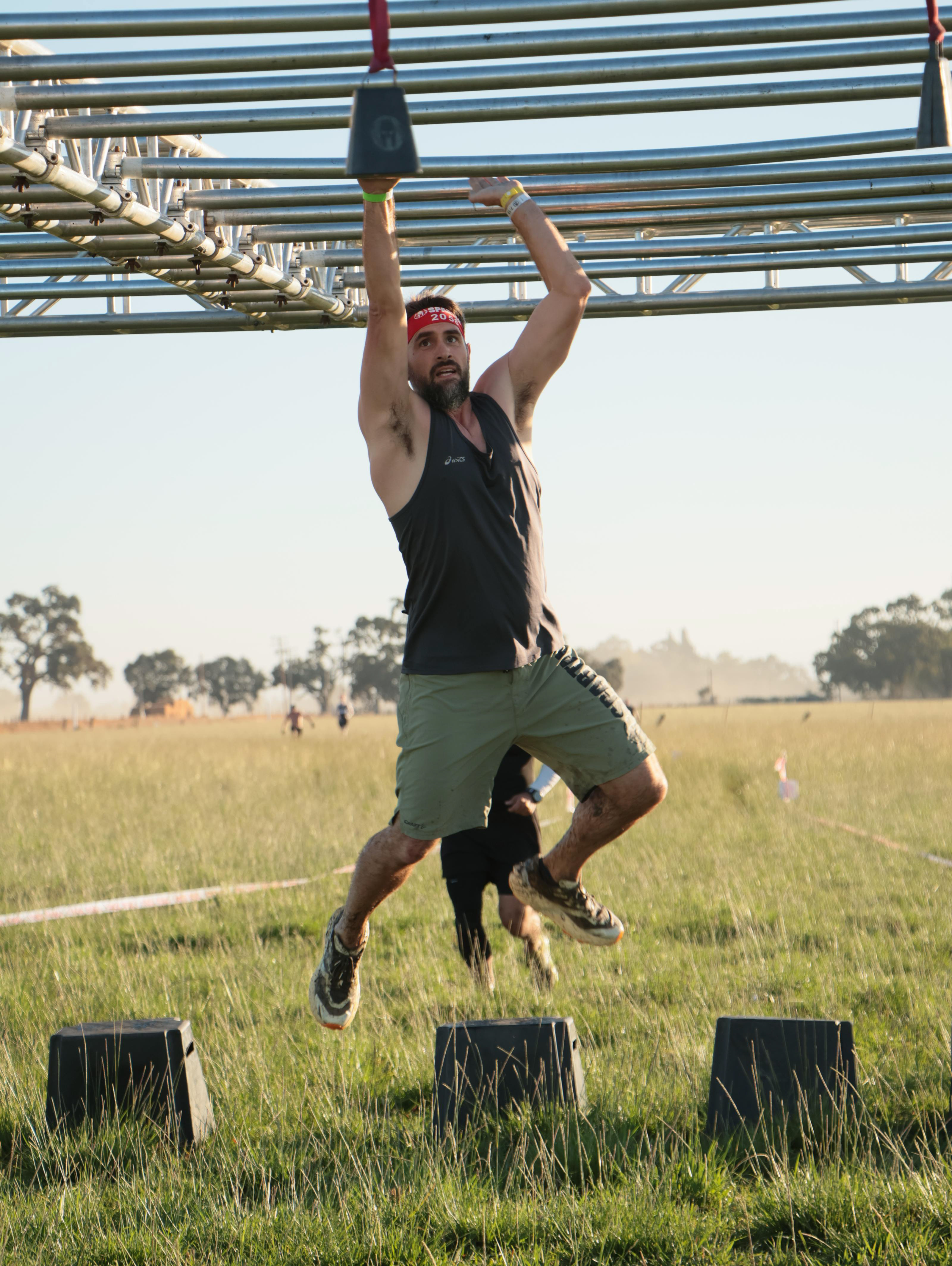 Spartan Race athlete crossing an overhead obstacle during competition.