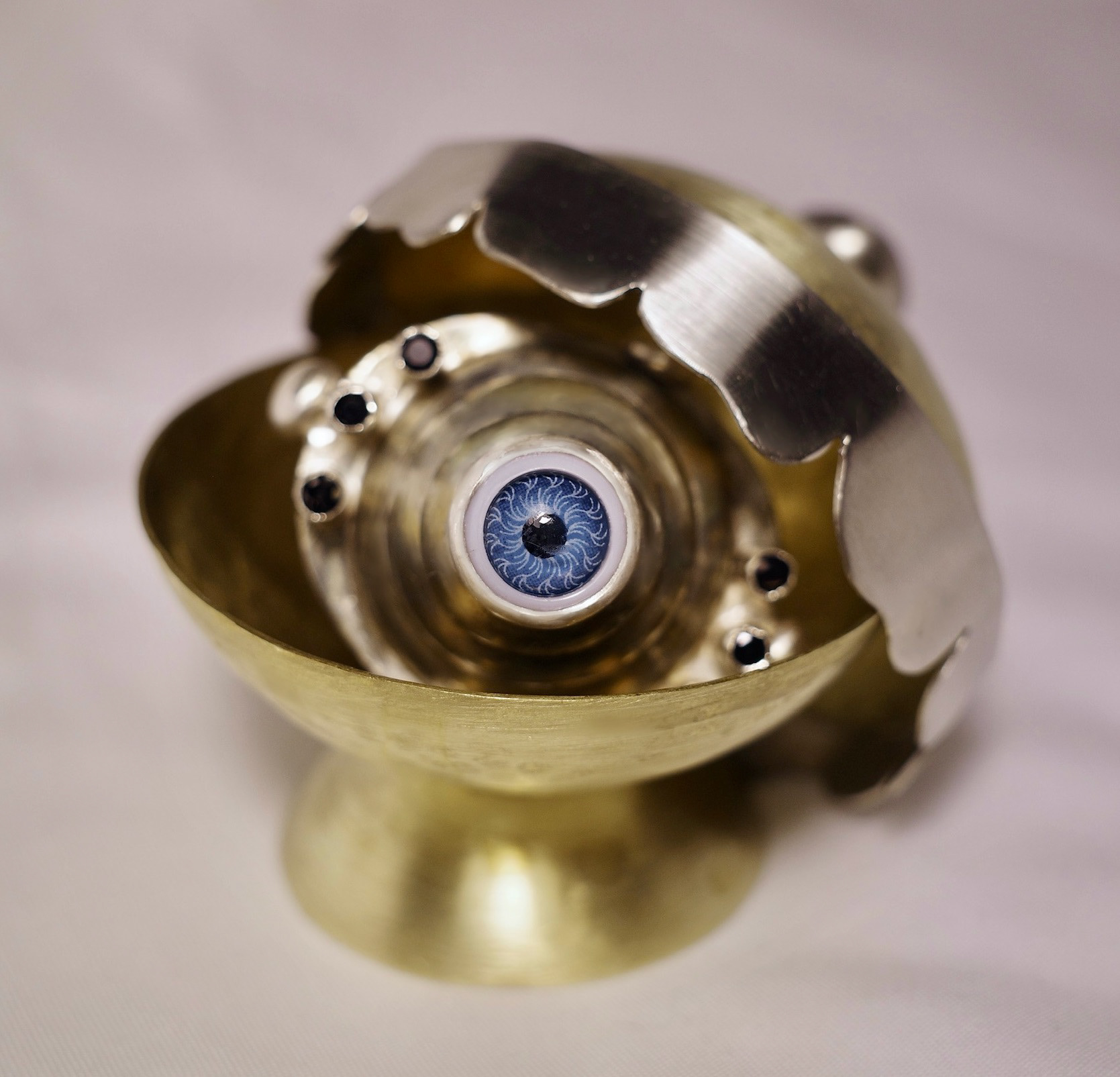 "teary eye, crooked smile" - brass, nickel silver, sterling silver tubing, black spinel stones and plastic eye - march 2023