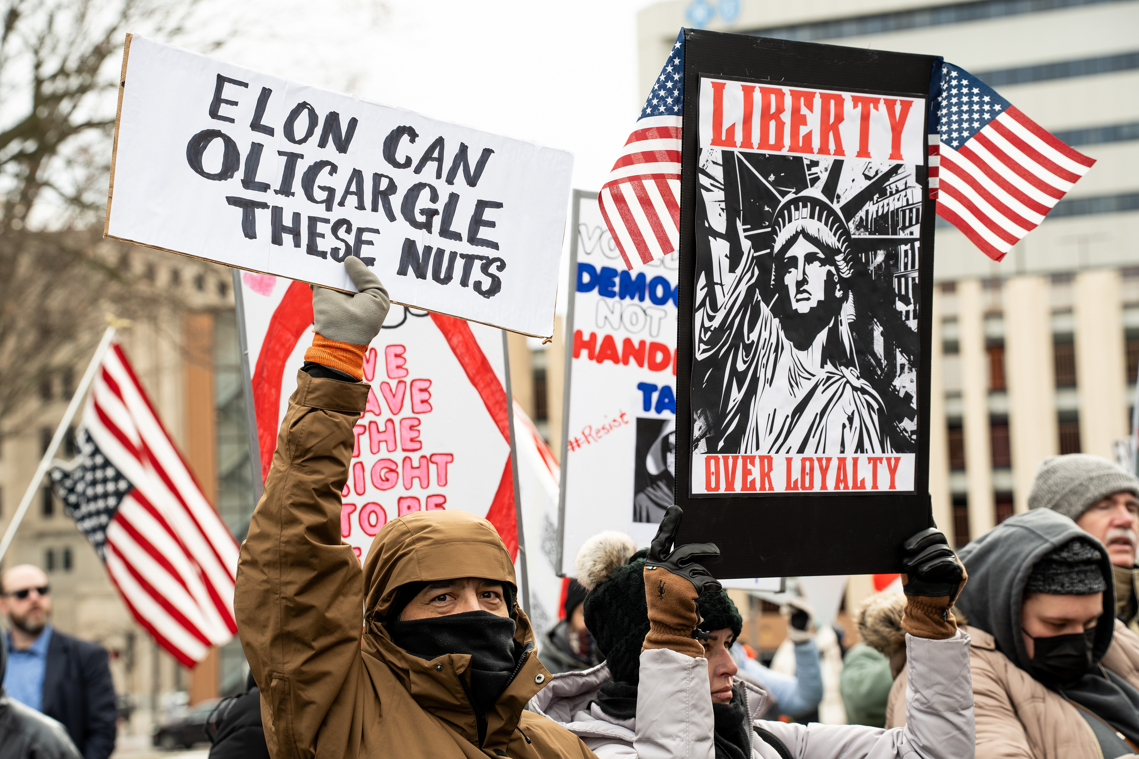 Protesters carry signs and United States flags at the Michigan Capitol Building in Lansing, Michigan on Feb. 5, 2025. Protesters gathered at the Michigan Capitol Building to demonstrate against President Donald Trump's cascade of executive orders.
