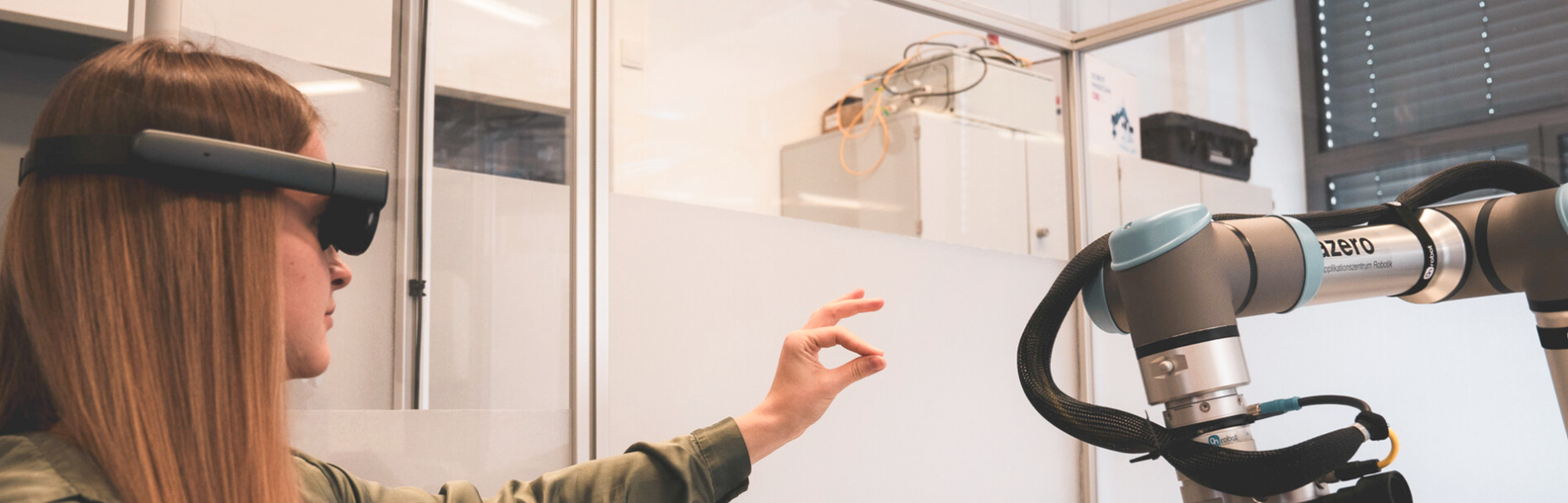 Woman wearing an AR-headset controlling a collaborative robotic arm with gestures in a lab environment