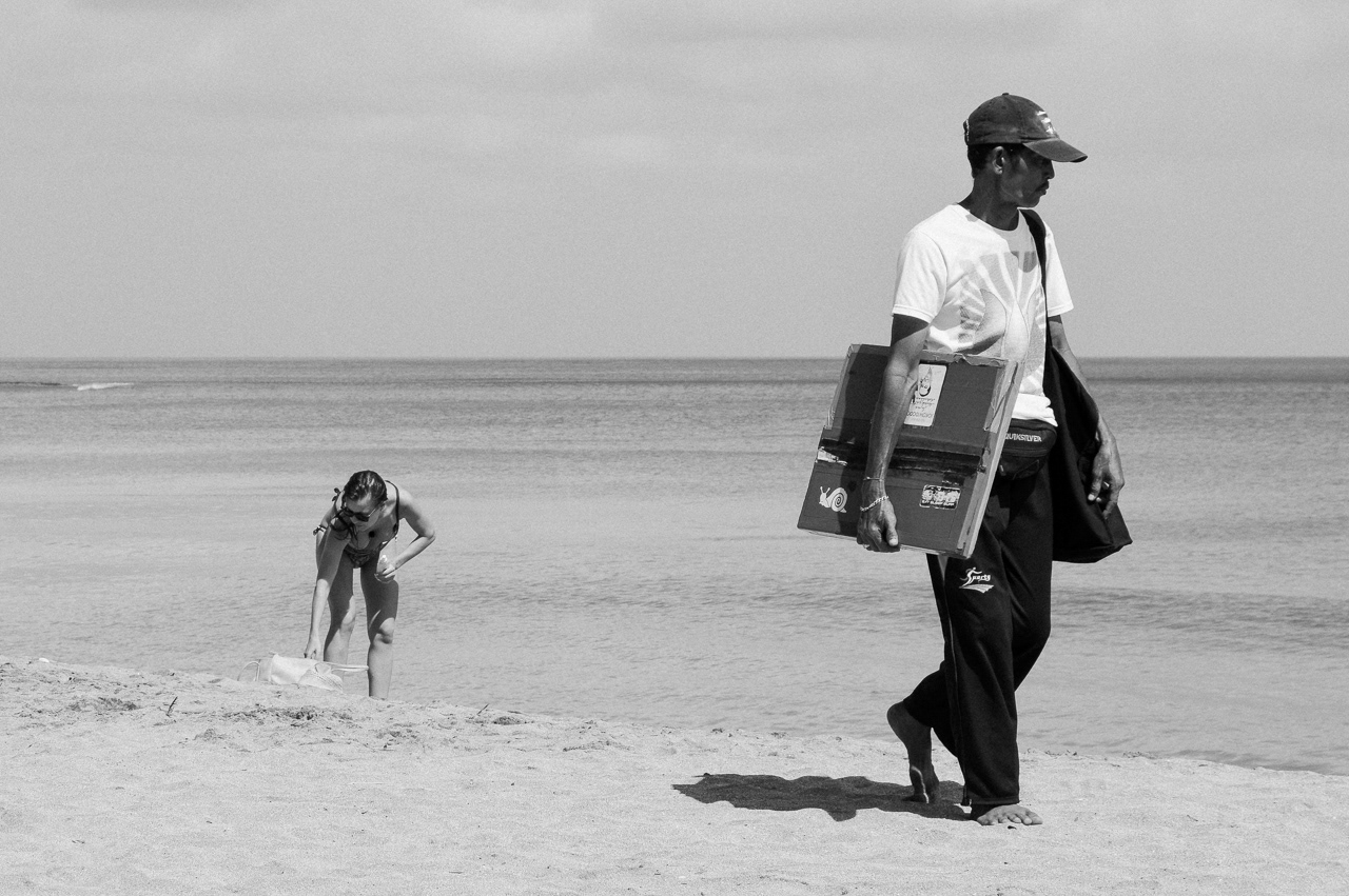 Sunbather and Pedagang Keliling. Kuta, 2014.