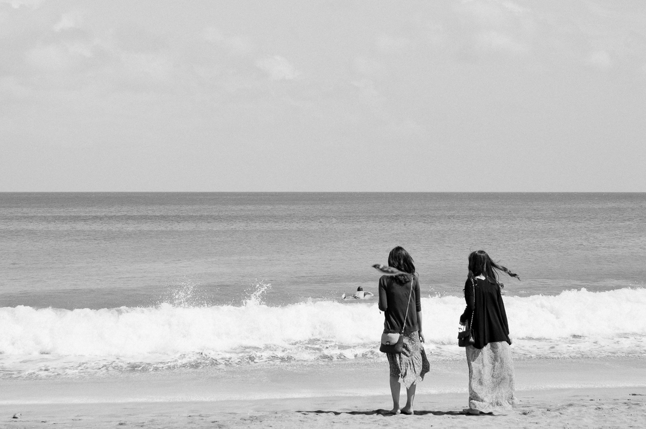 Two Japanese tourists gazing by the shoreline. Kuta, 2014