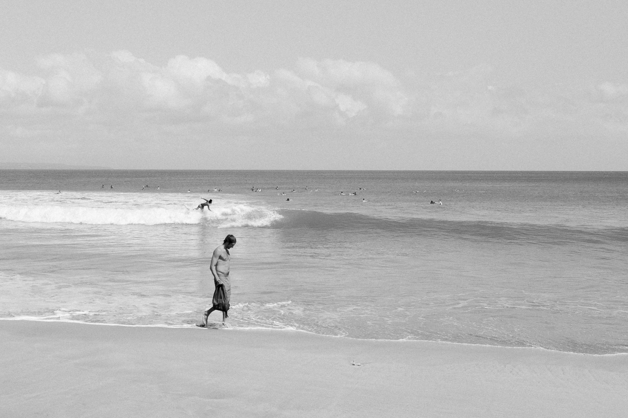 A surfer and a walker going towards same direction. Kuta, 2014.
